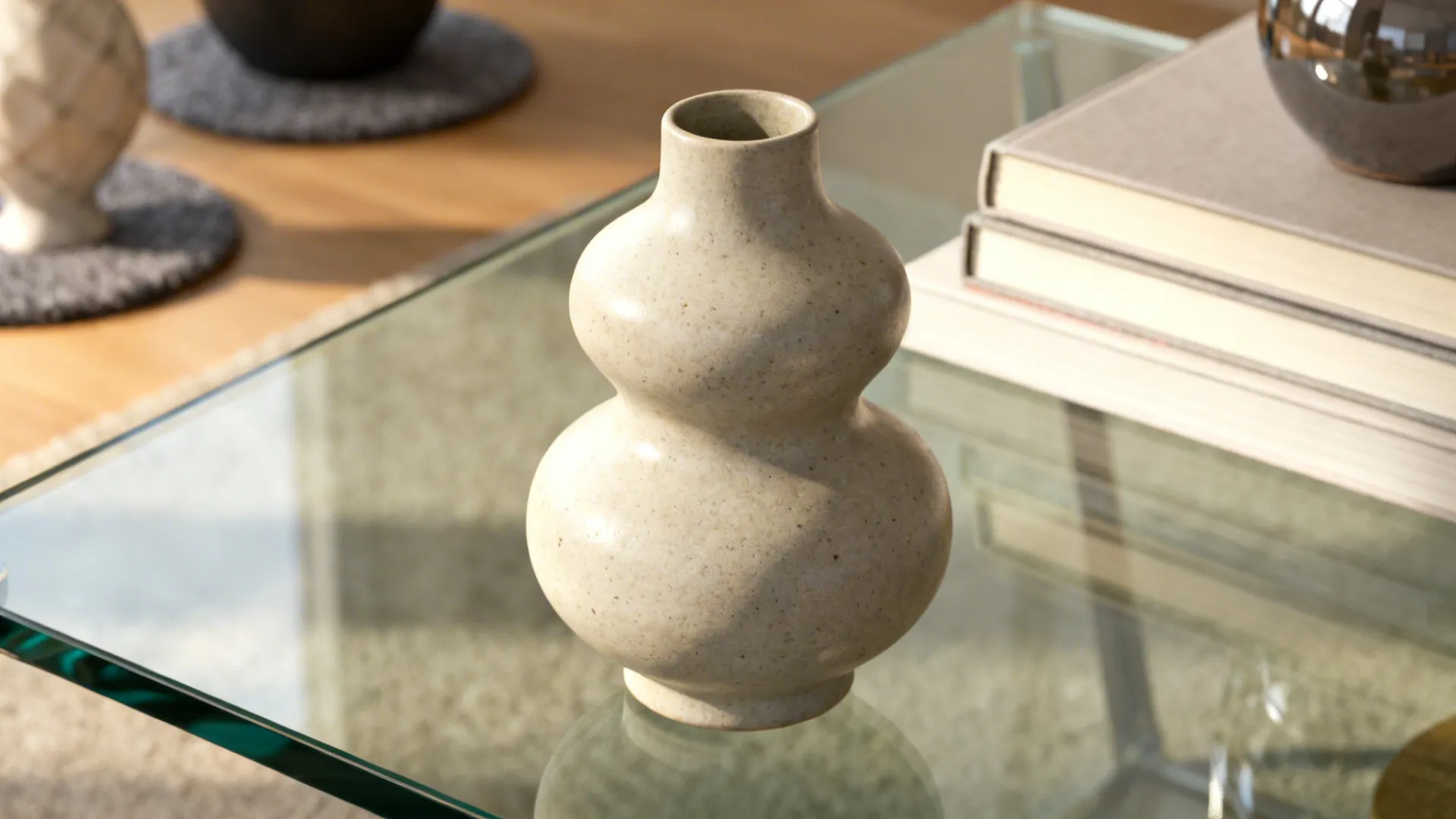 Sculptural ceramic vase centered on a clear glass tabletop with felt pads under decor.