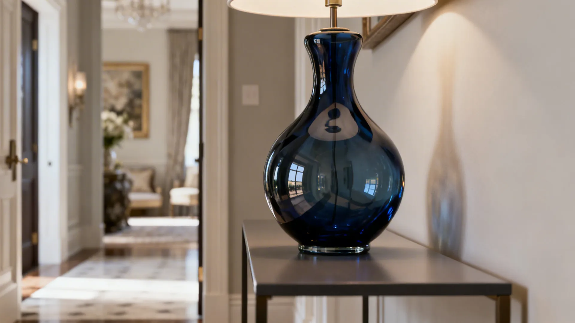 Sculptural navy blown-glass lamp reflecting light on a slim console