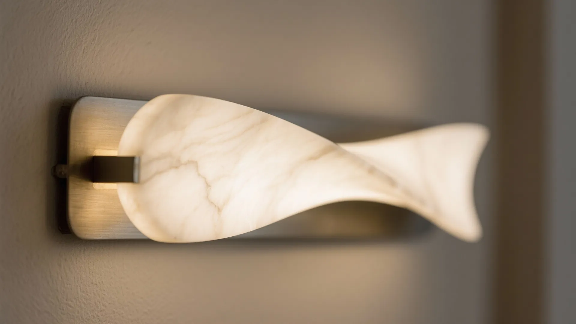 Modern white wave wall light fixture glowing with warm light on a light grey wall