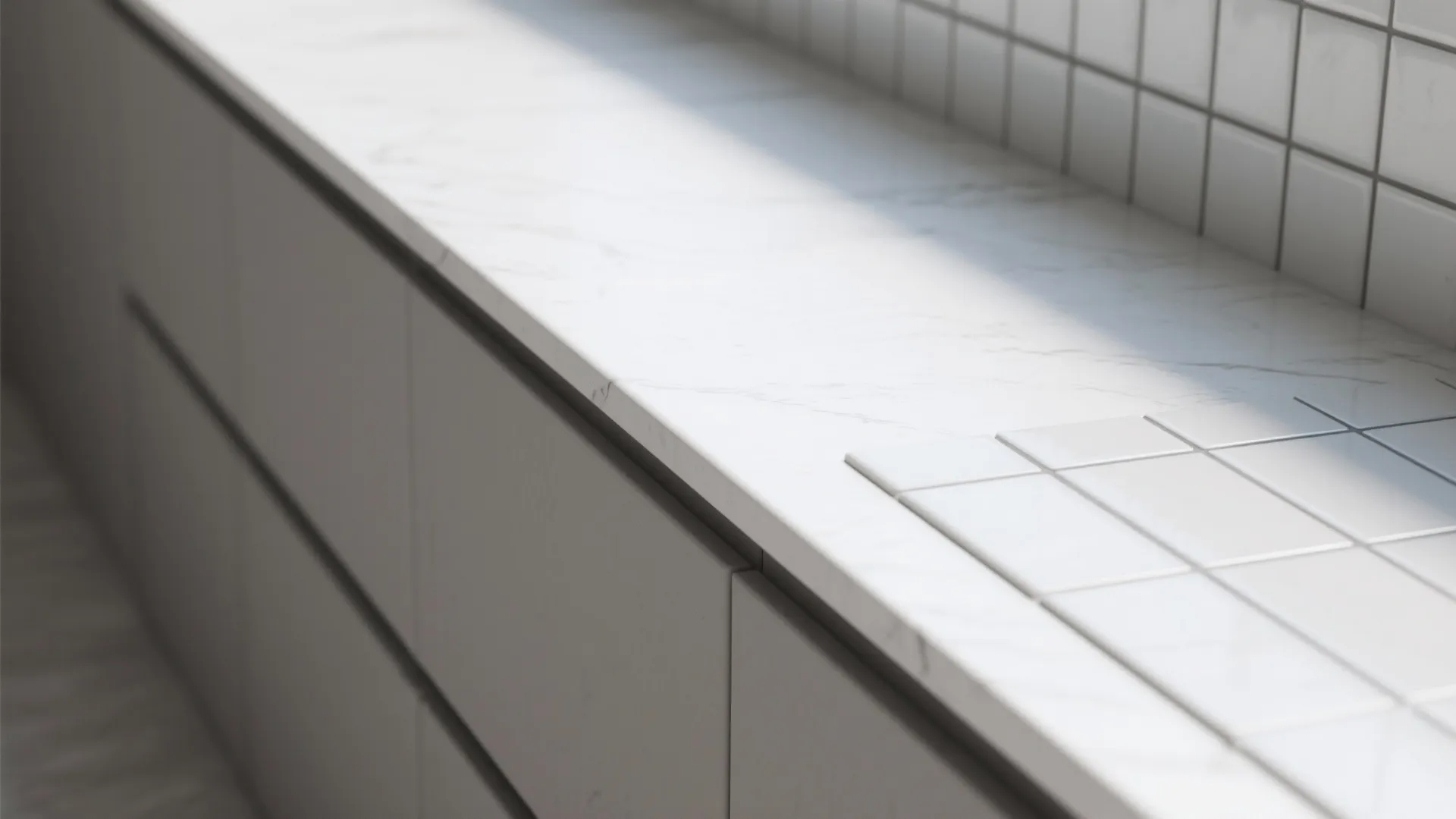 Modern white marble kitchen countertop with grey cabinets and square wall tiles in natural light