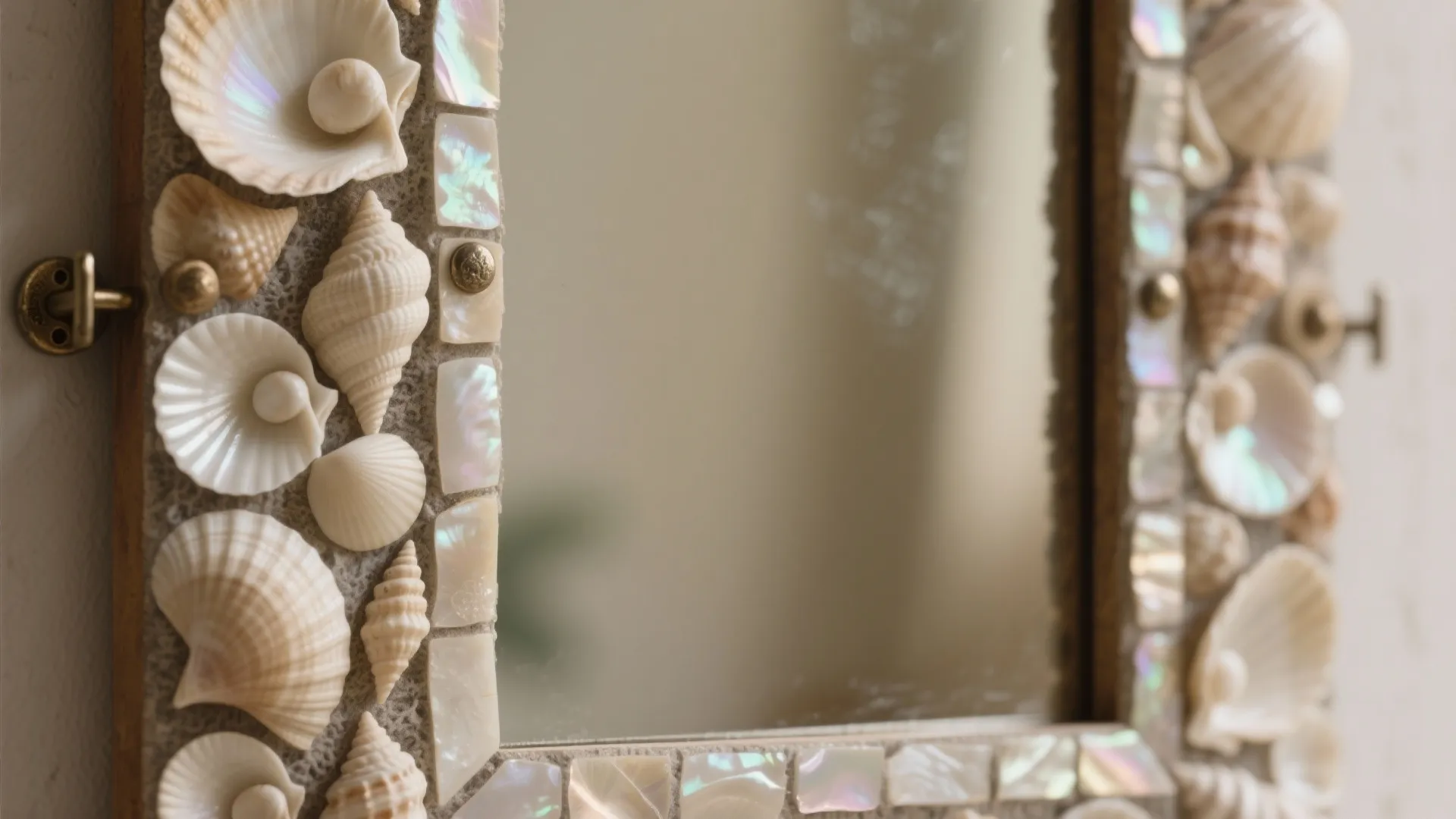 Close-up of a wall mirror decorated with various white seashells and shiny pearl-like mosaic tiles