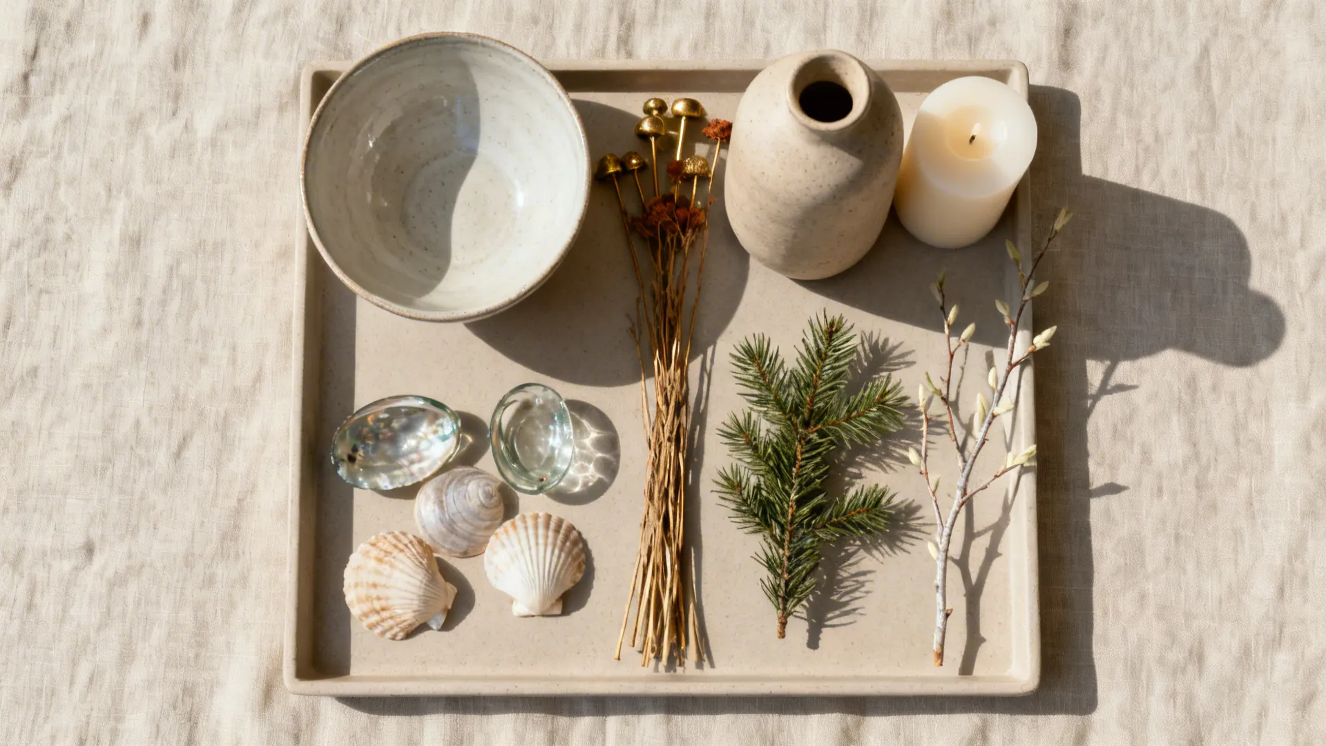 Top-down flat lay of a tray, bowl, vase, candles, and seasonal accents arranged on a linen surface.