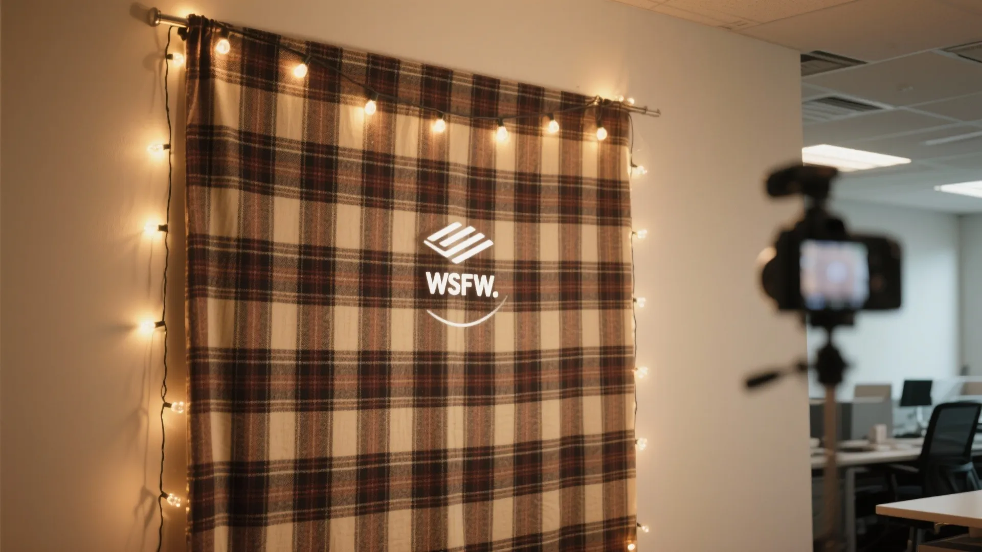 Plaid fabric backdrop with warm string lights hanging on an office wall for video filming