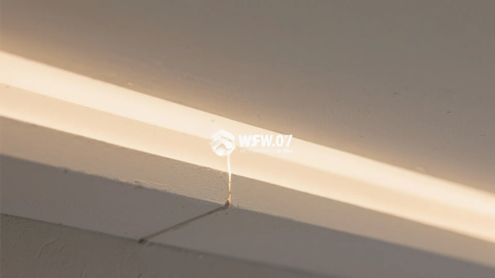 Close up view of a white wall panel with a thin gap showing hidden light strip