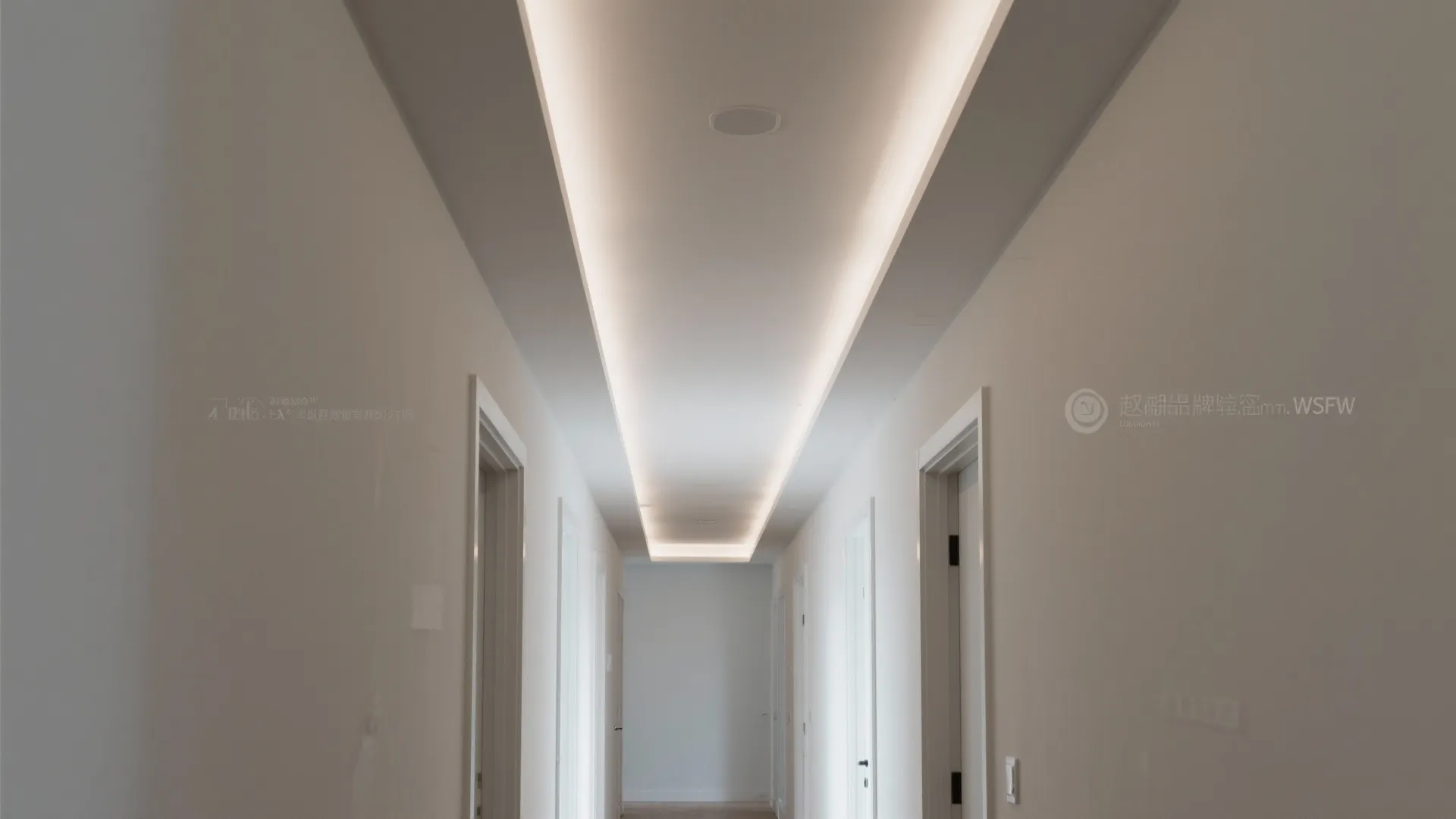Minimalist white hallway with a long rectangular recessed ceiling light and several white interior doors
