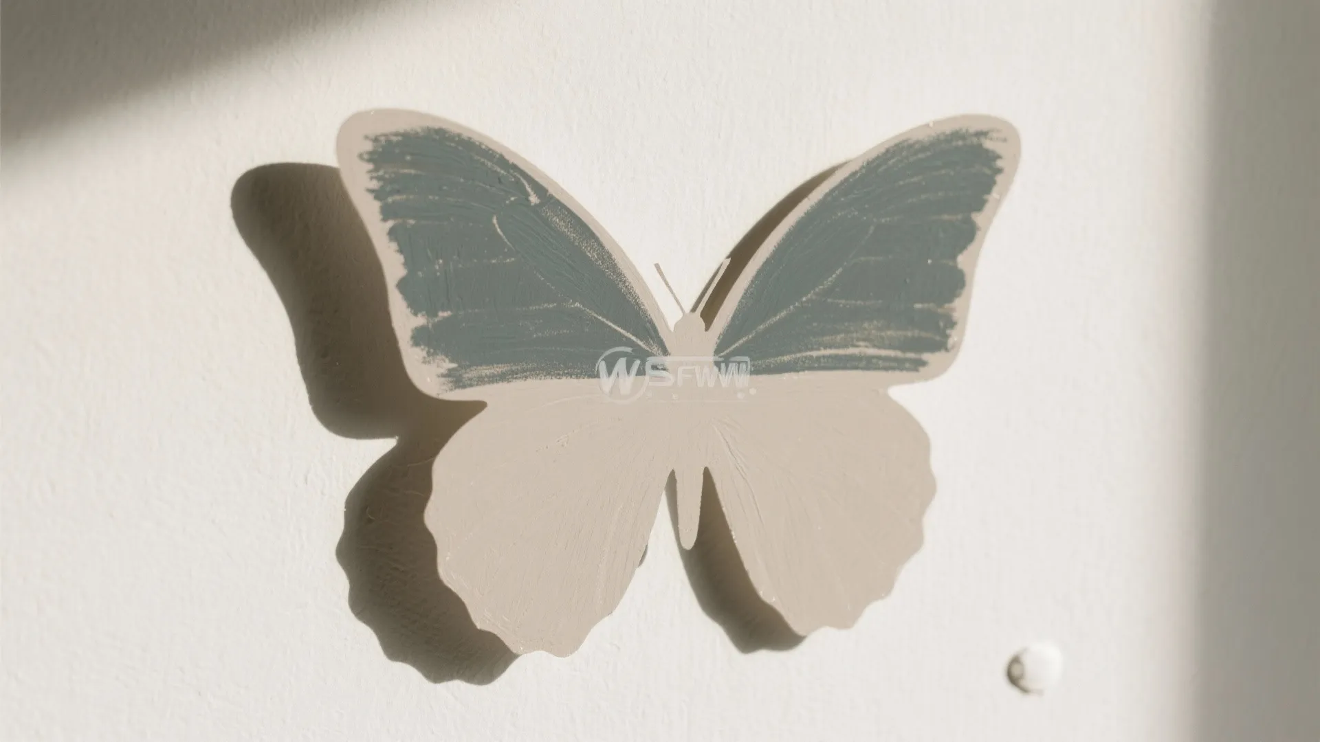 Close up of butterfly wall sticker with blue and beige wings on a white wall