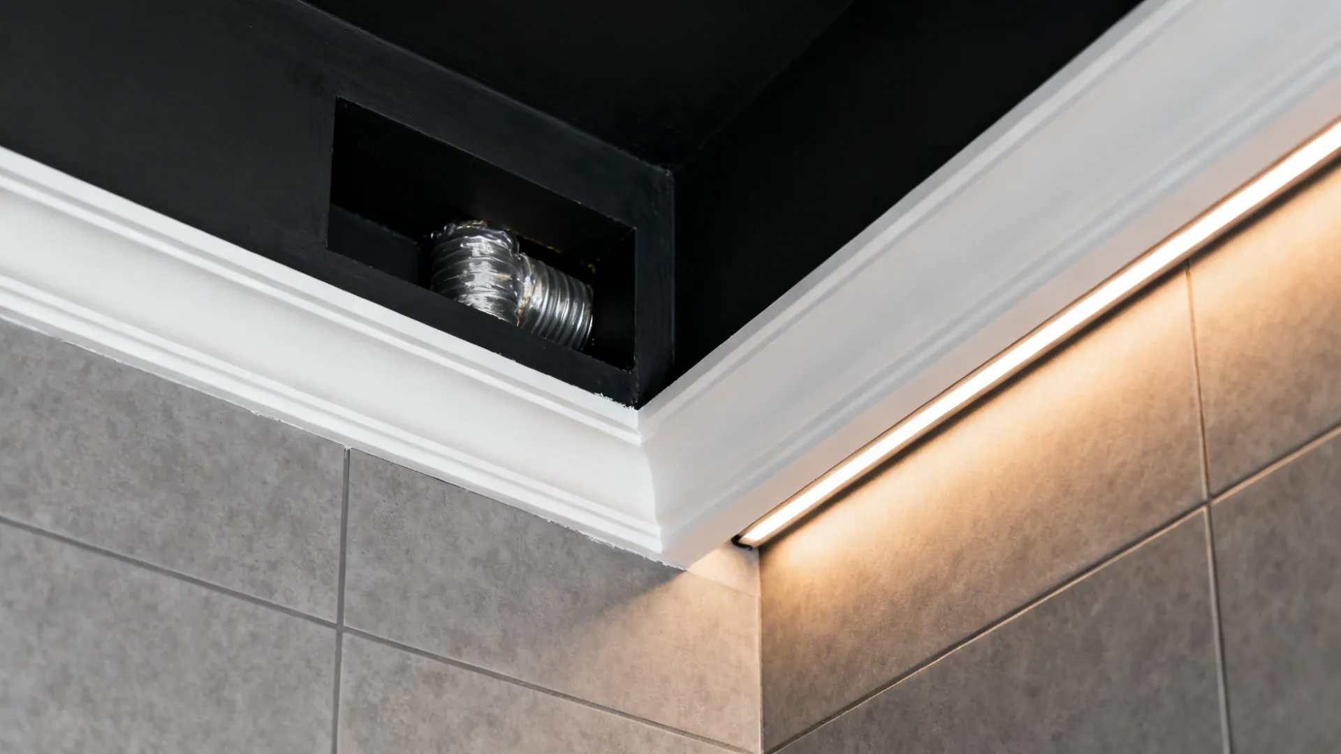 Macro of a matte black shadow-line reveal integrating a concealed vent with wall-washer light.