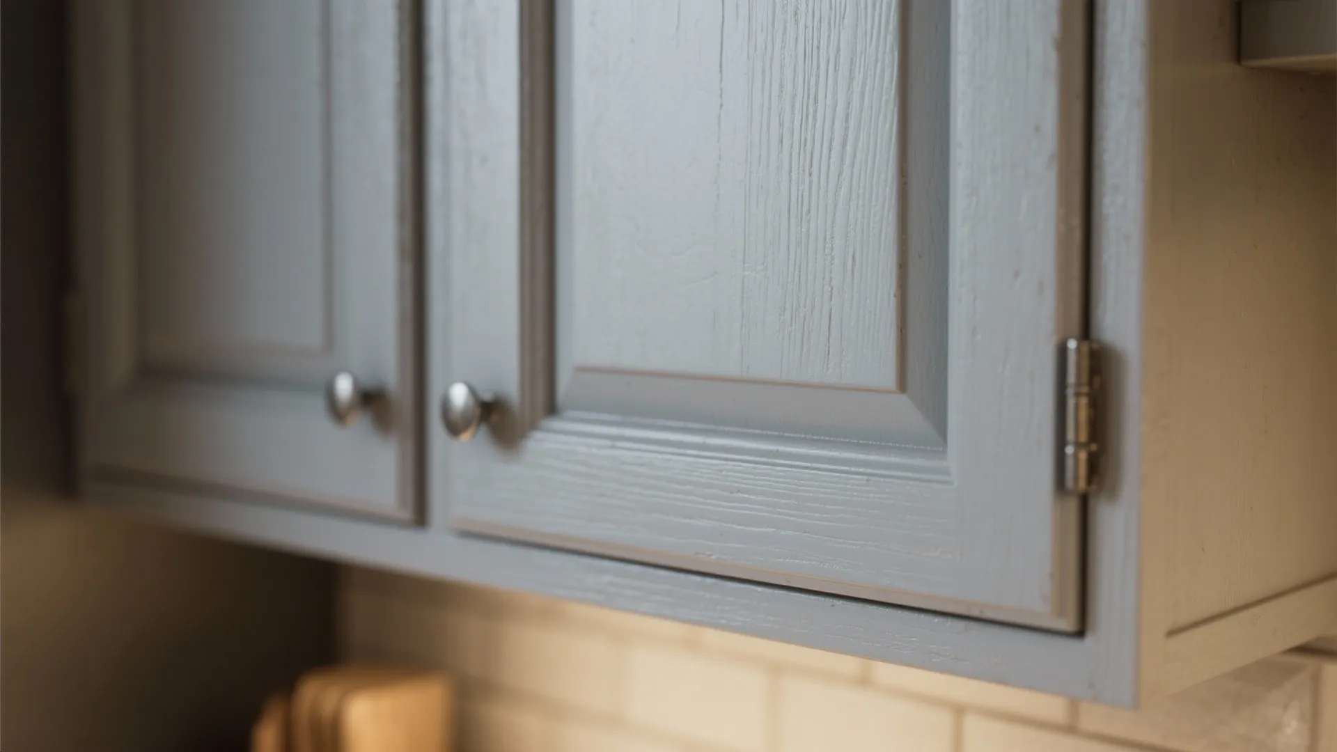 Close-up of a grey shaker cabinet door showing recessed panel and slim rail profile.