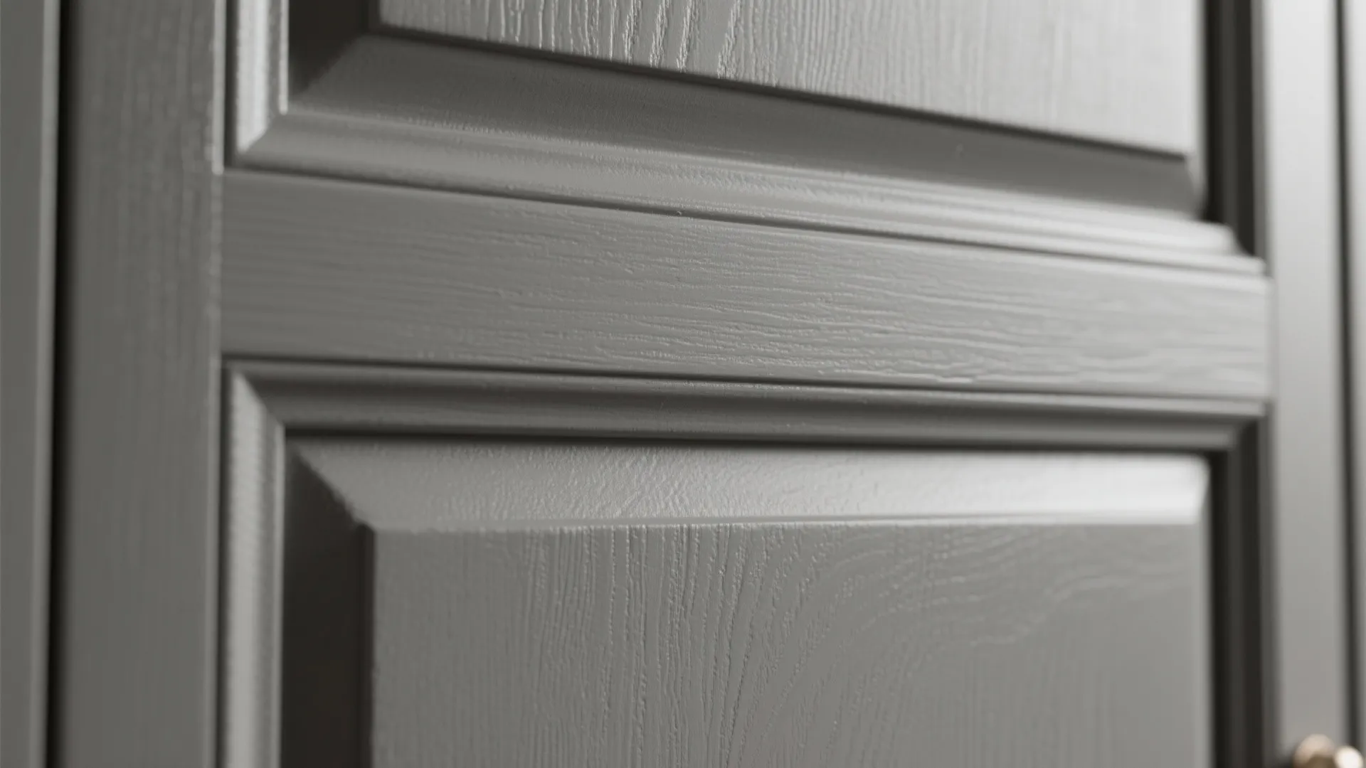 Close up view of grey cabinet door with wood grain texture and classic wall panel