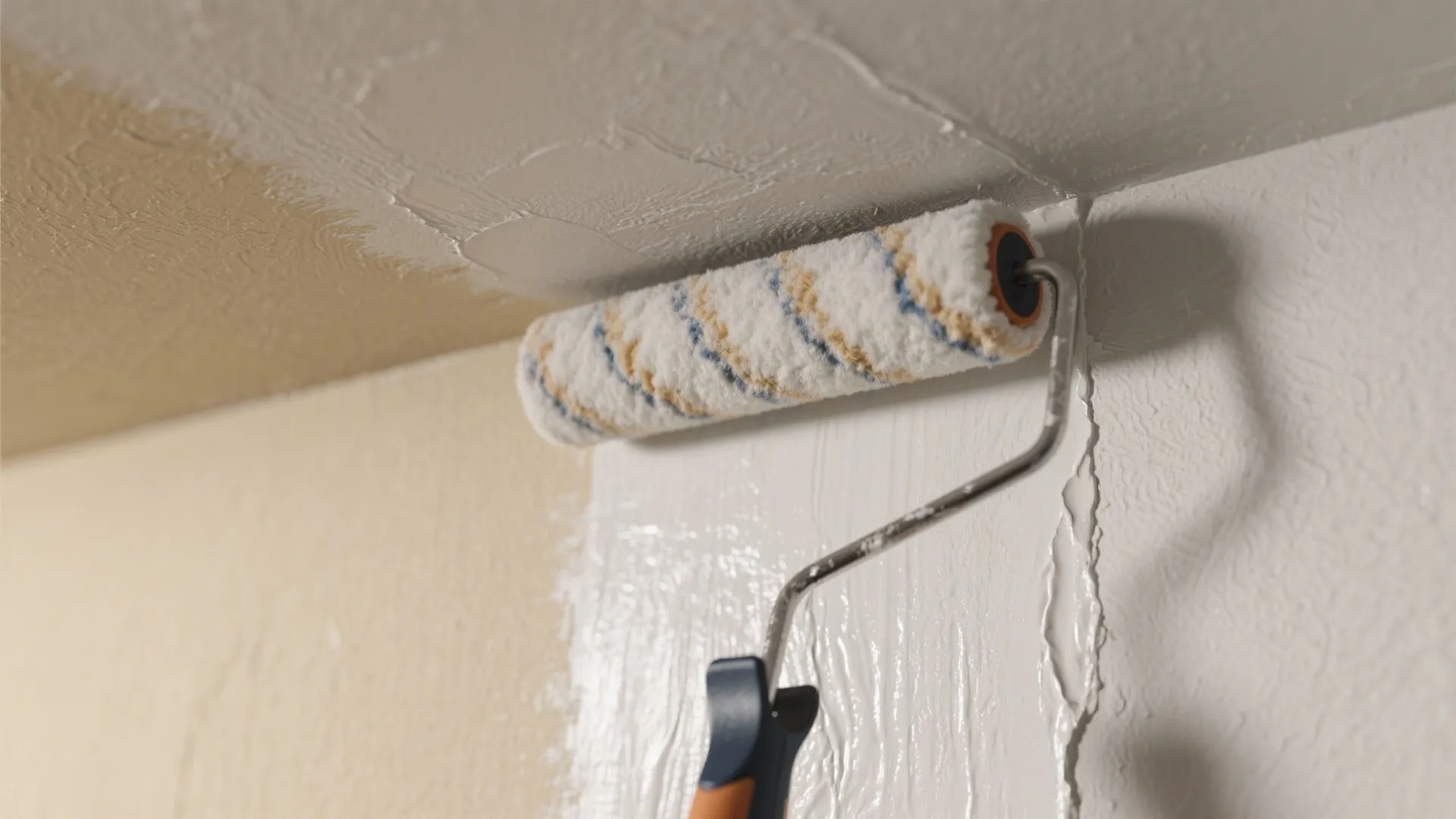 Close-up of a roller applying flat ceiling paint next to an eggshell wall, showing sheen difference.