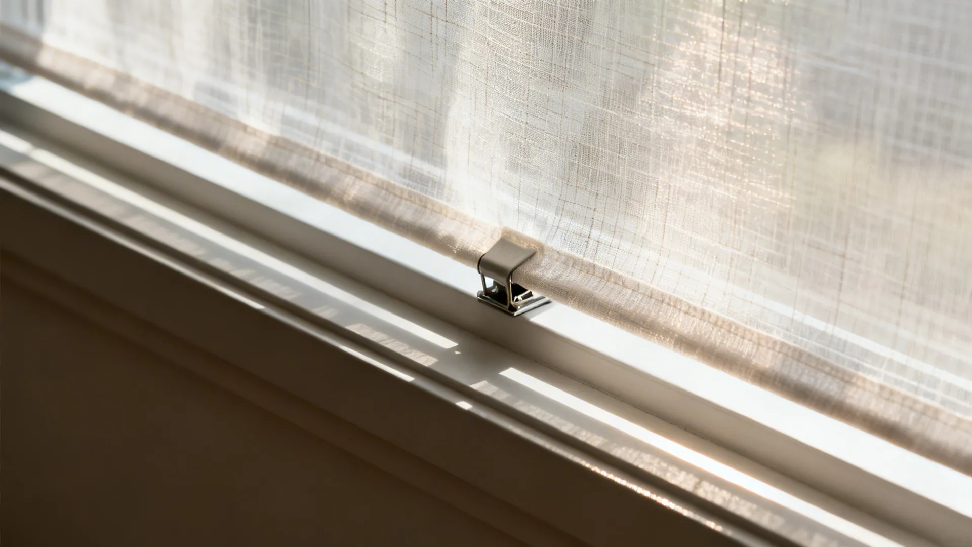 Macro of sheer fabric acting as a light diffuser on a clean window frame in soft daylight.