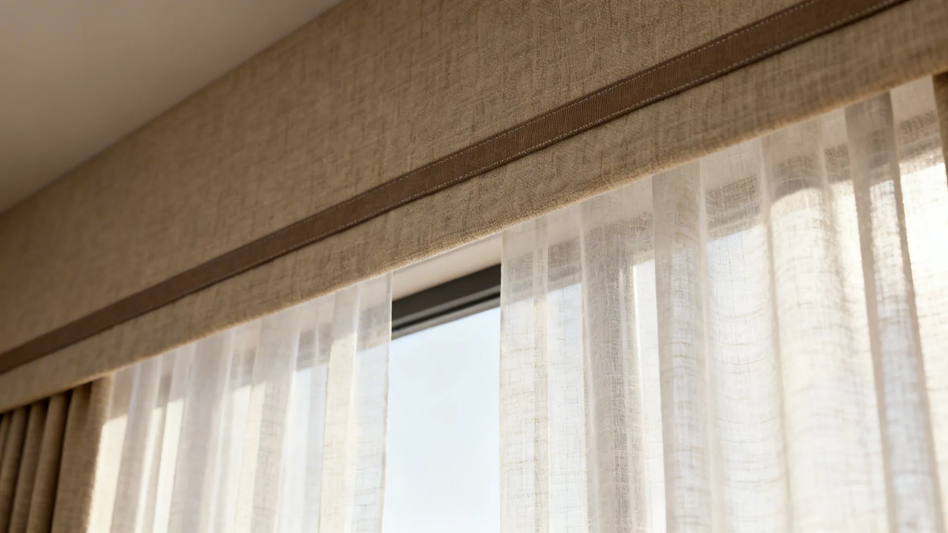 Close up of a beige fabric curtain top over white sheer curtains in a bright room