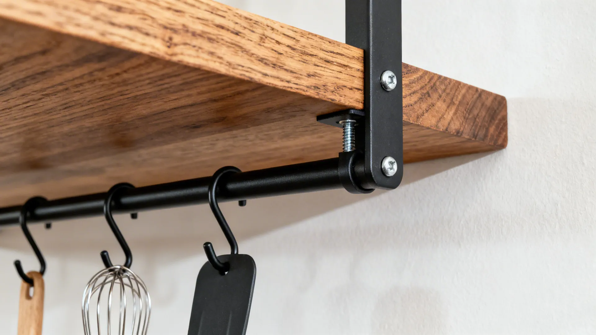 Close up of wooden shelf with black metal hanging rod and hooks for cooking tools