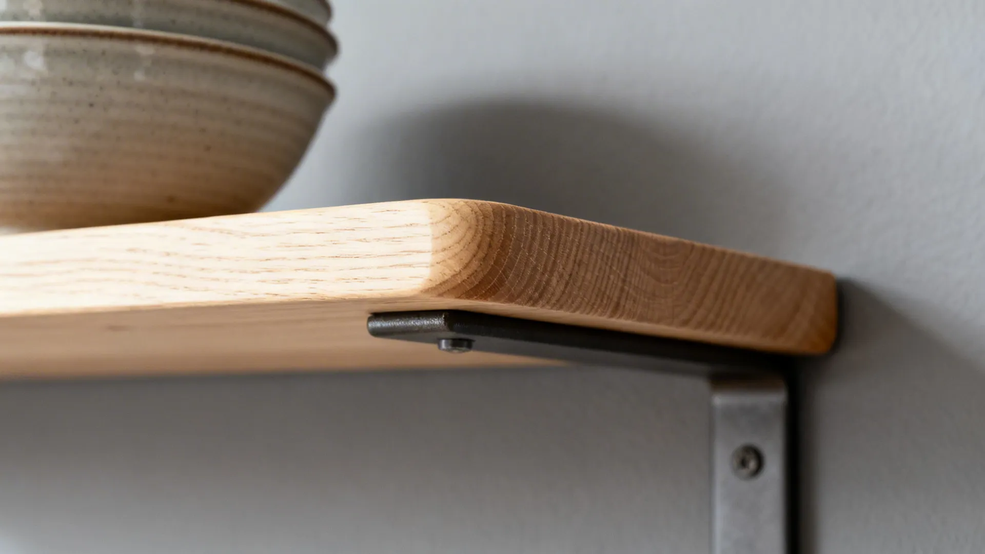 Macro detail of birch shelf edge with matte finish and metal bracket.
