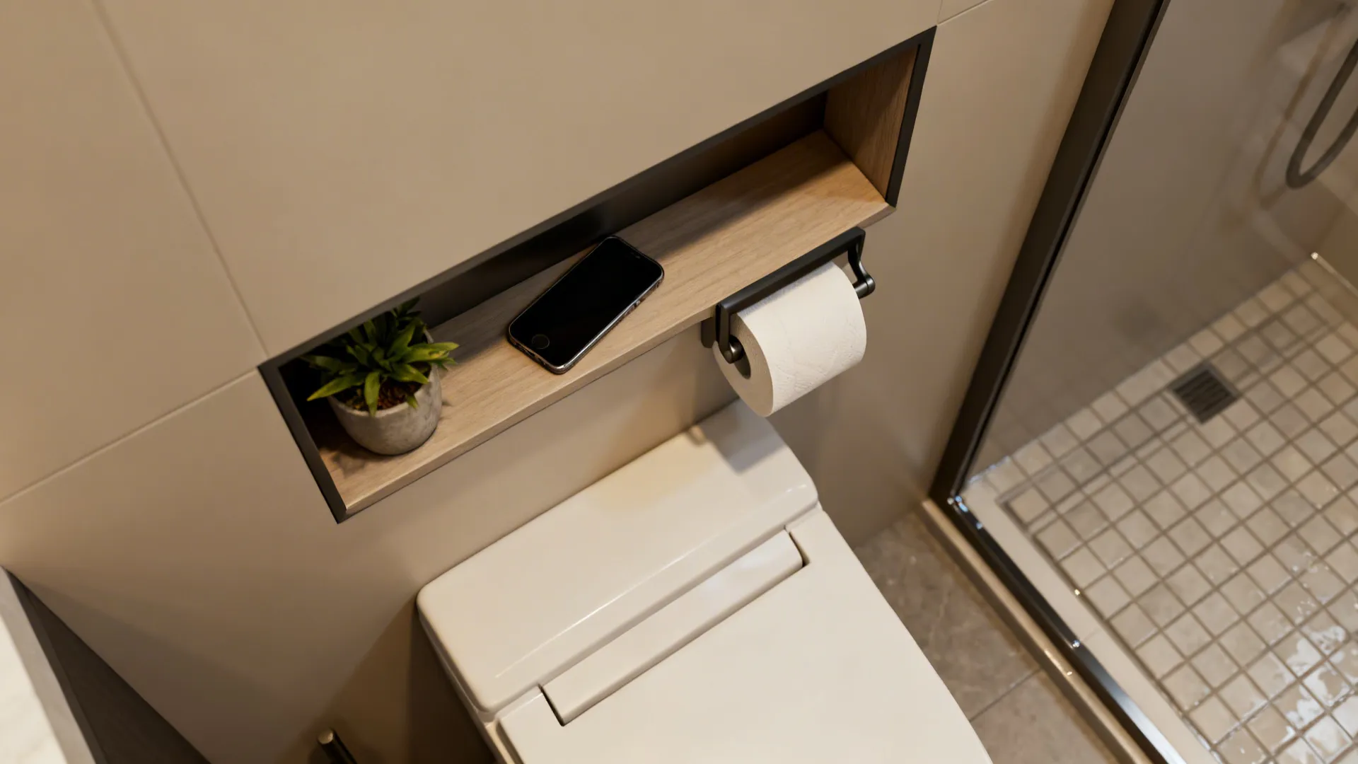 Wall niche above toilet with wooden shelf holding a smartphone, green plant, and paper roll