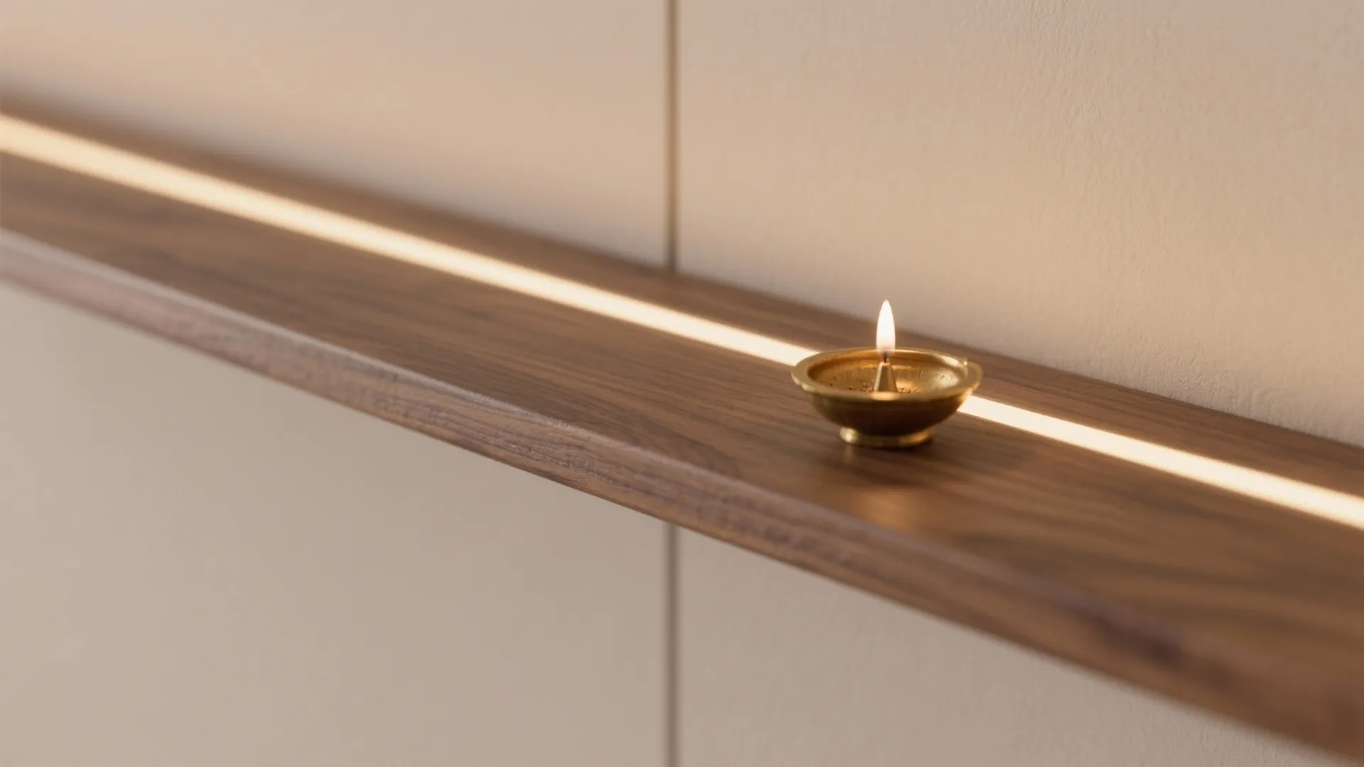 Close-up of oak shelf with integrated warm LED illuminating a brass diya.