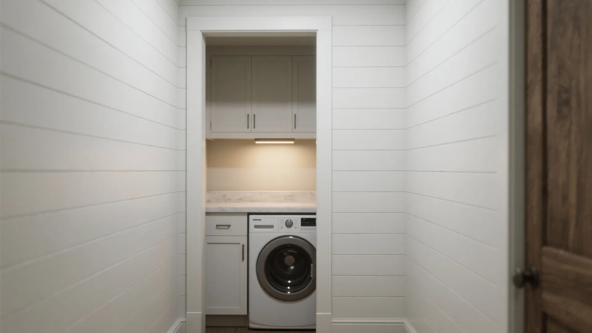Small laundry nook with white wall panel design featuring a single washer and grey cabinets