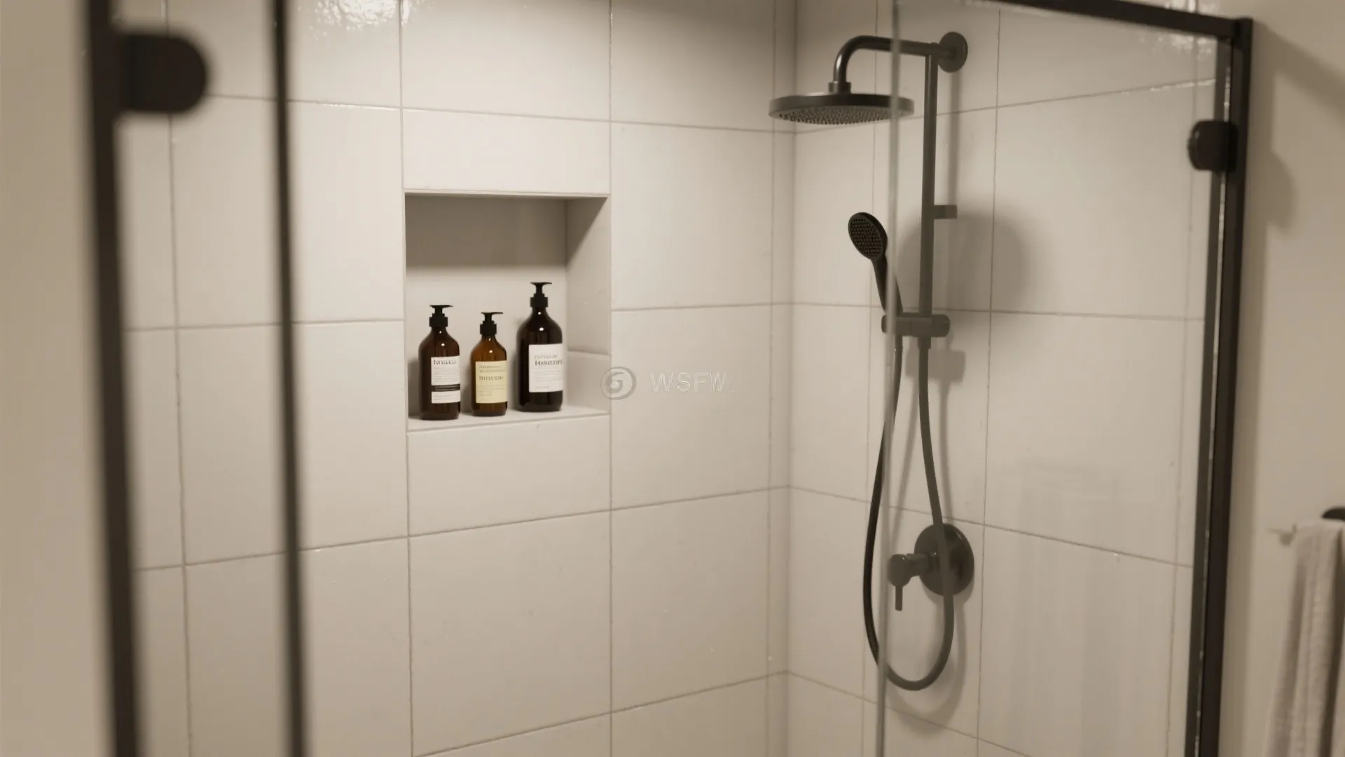 White tiled shower wall with a recessed shelf three brown bottles and a black shower head