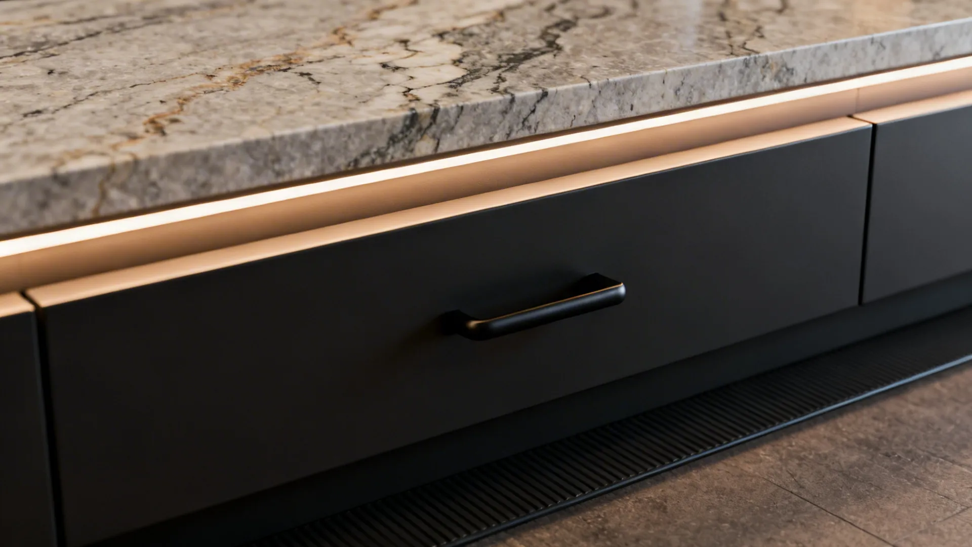 Close-up of a continuous single-level stone countertop with undercabinet lighting and lever-handle drawer.