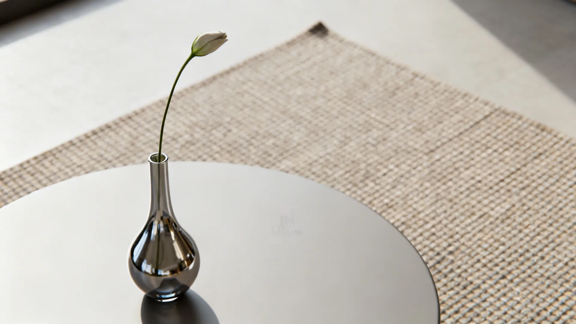 Single sculptural bud vase with one stem on a round table, minimalist composition.