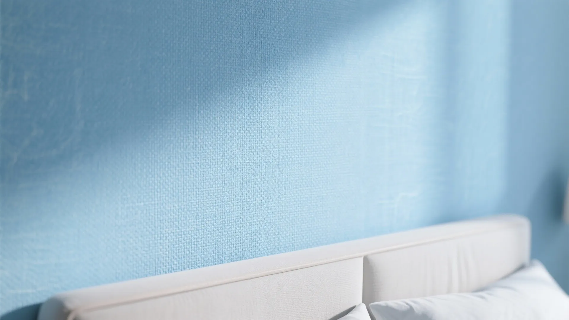 Macro view of soft sky blue linen-textured wallpaper with subtle daylight highlights.