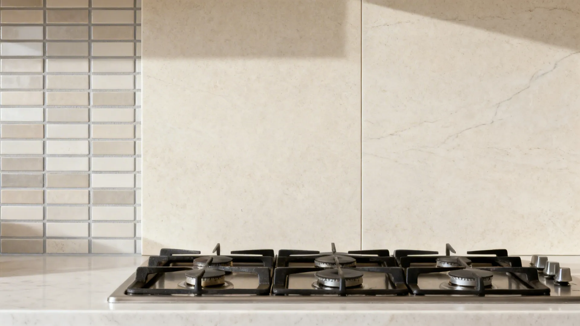 Before-and-after comparing many grout lines to a seamless stone slab backsplash.