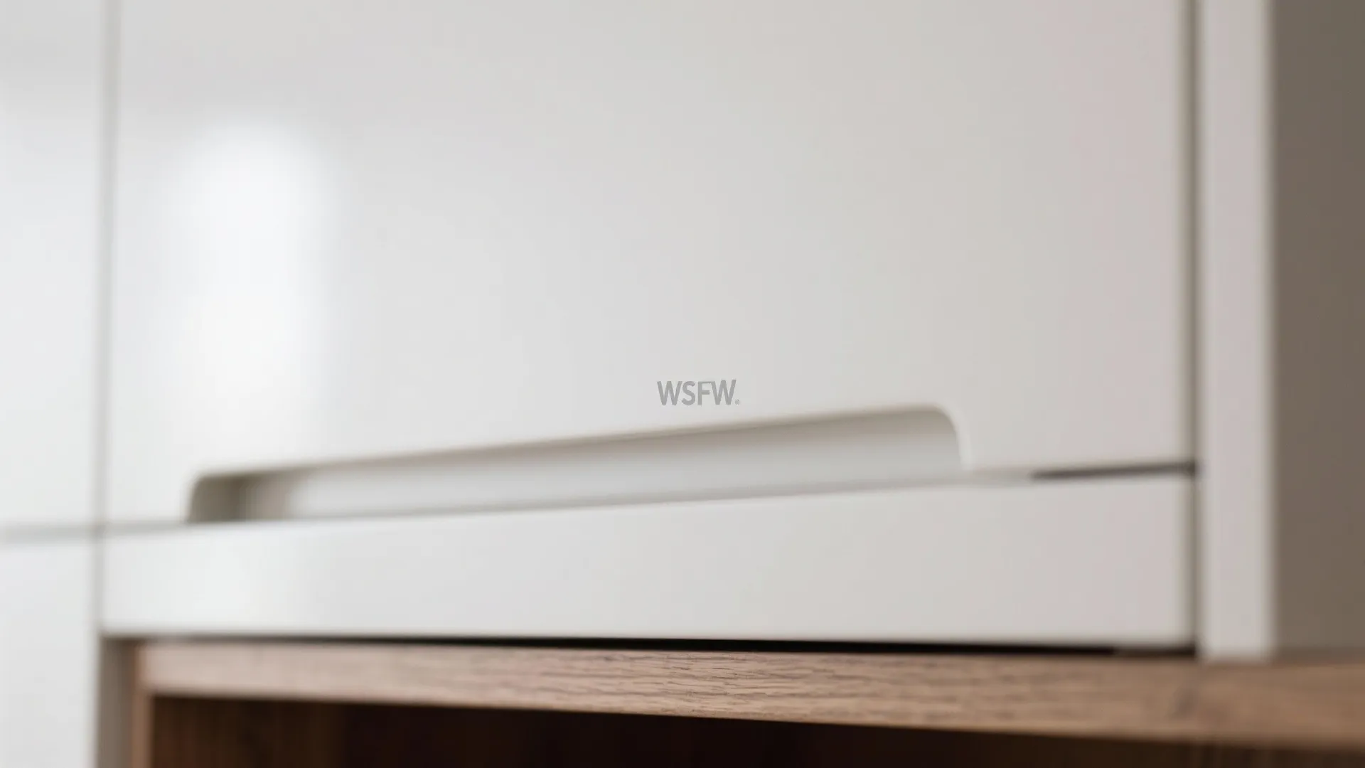 Close up of a white kitchen cabinet door featuring a smooth surface and integrated finger pull