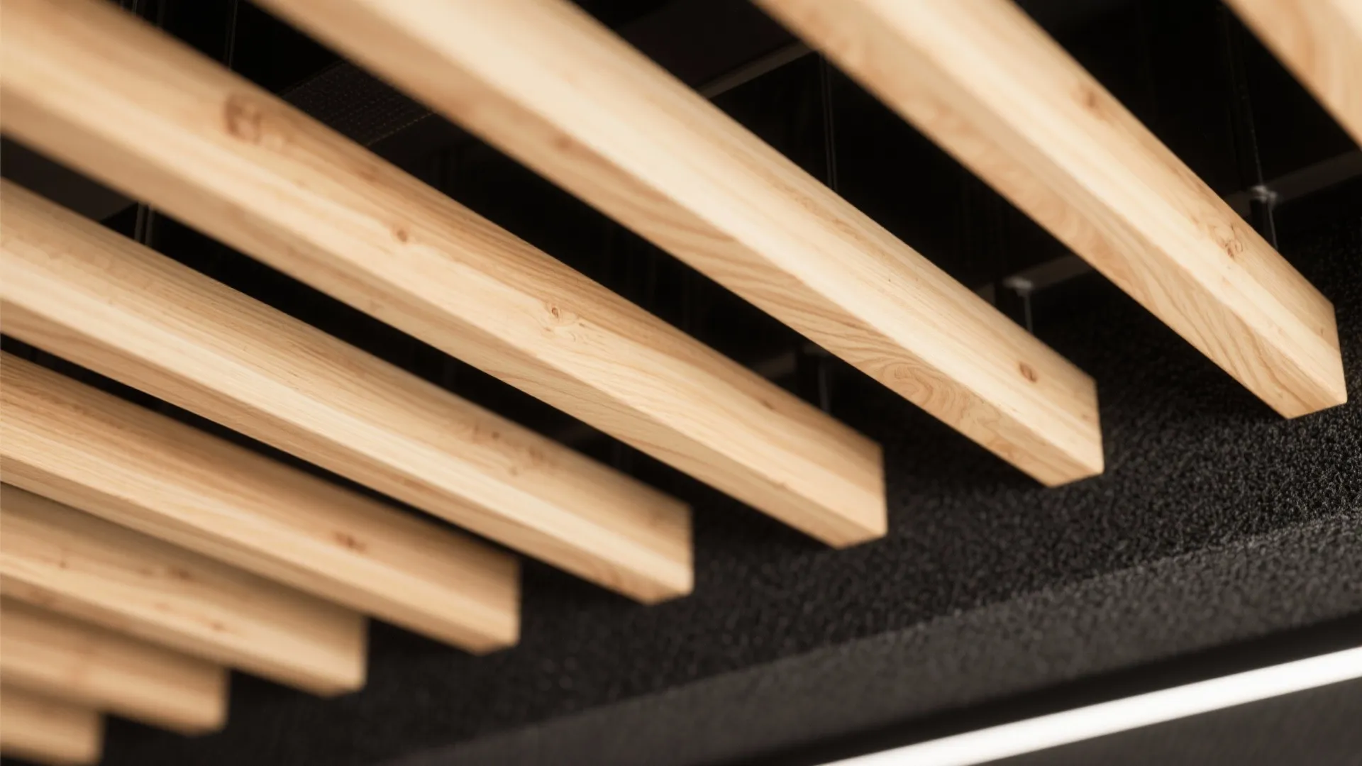 Close up view of parallel wooden ceiling slats with dark acoustic foam backing and natural light