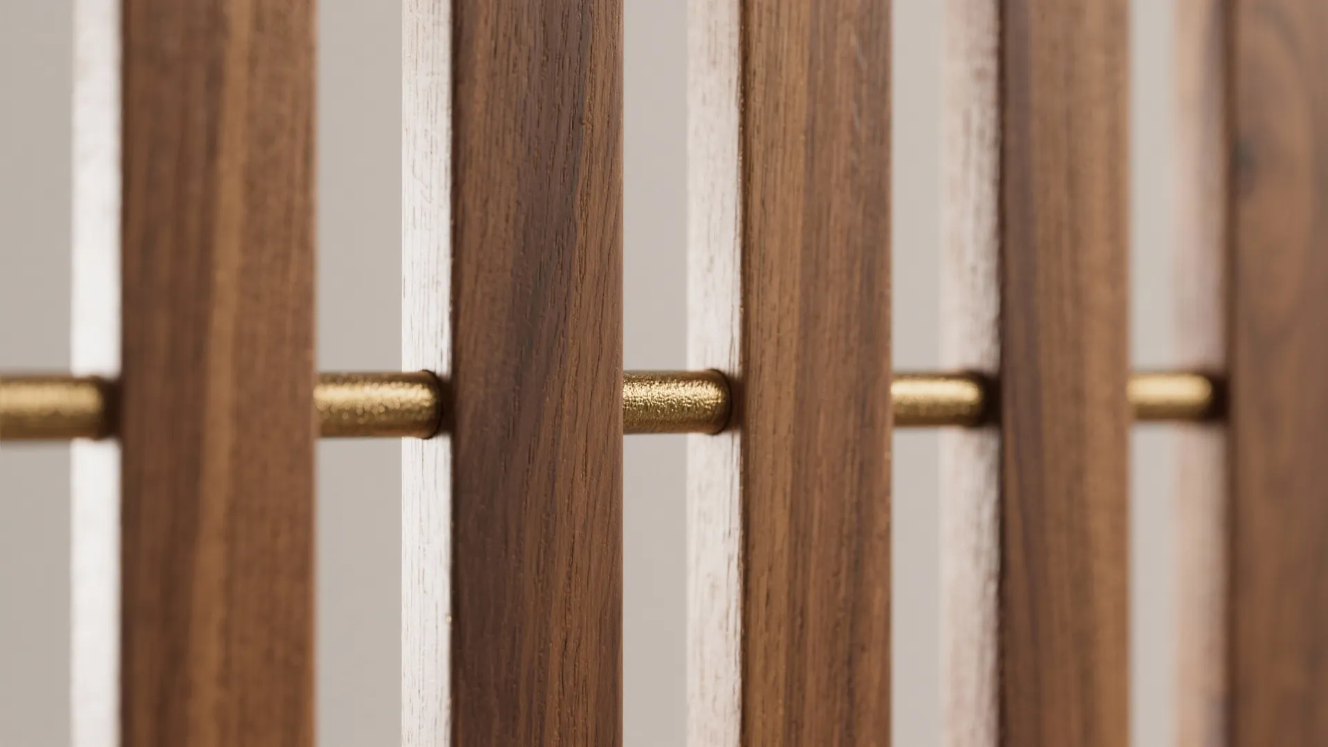 Close up of vertical wooden wall panels connected by horizontal gold metal bars for room decoration