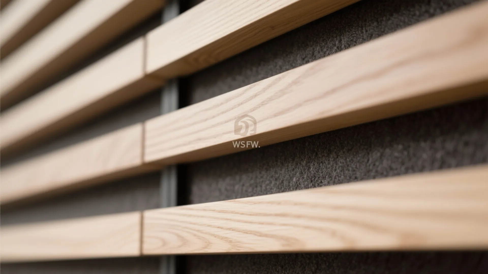 Close up view of horizontal light wood wall panels with a dark grey textured background