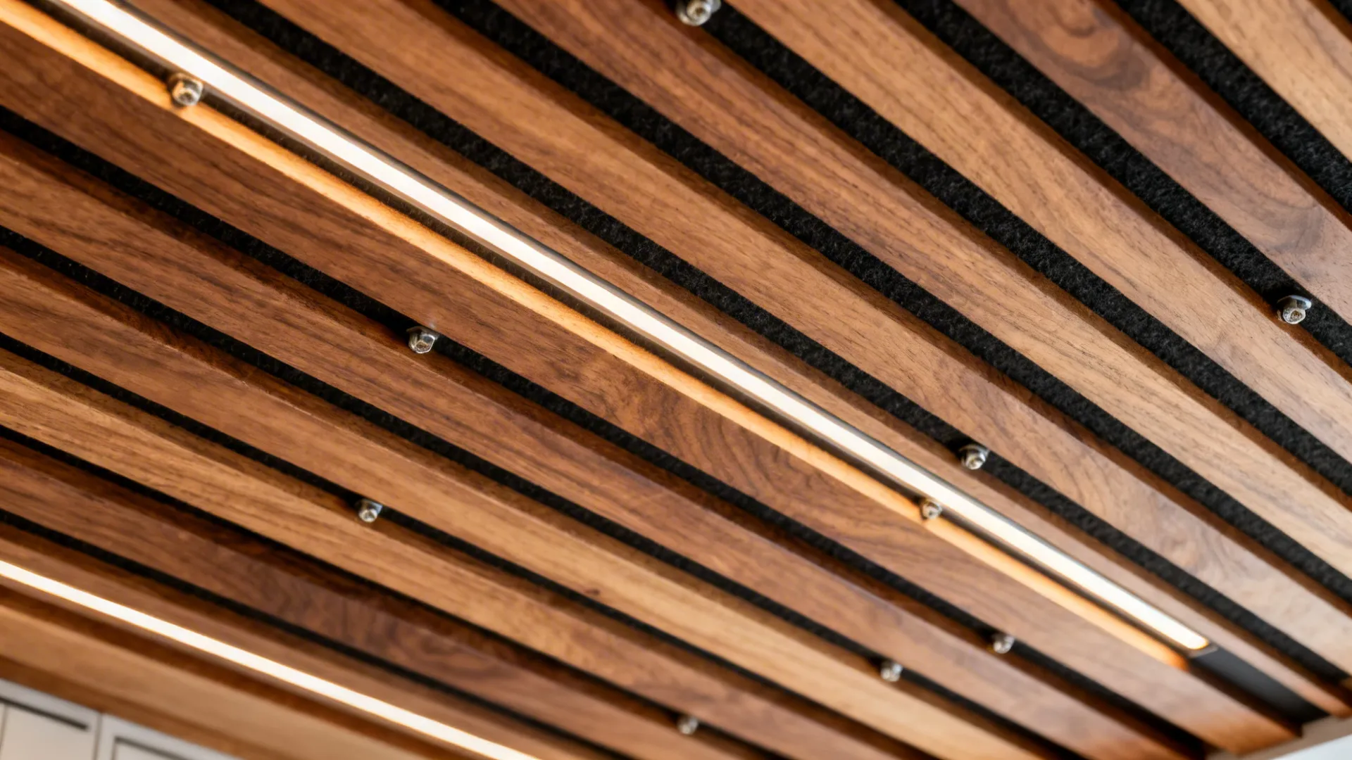 Close-up of sealed oak slats with black felt backing and a recessed linear LED softly washing the wood.