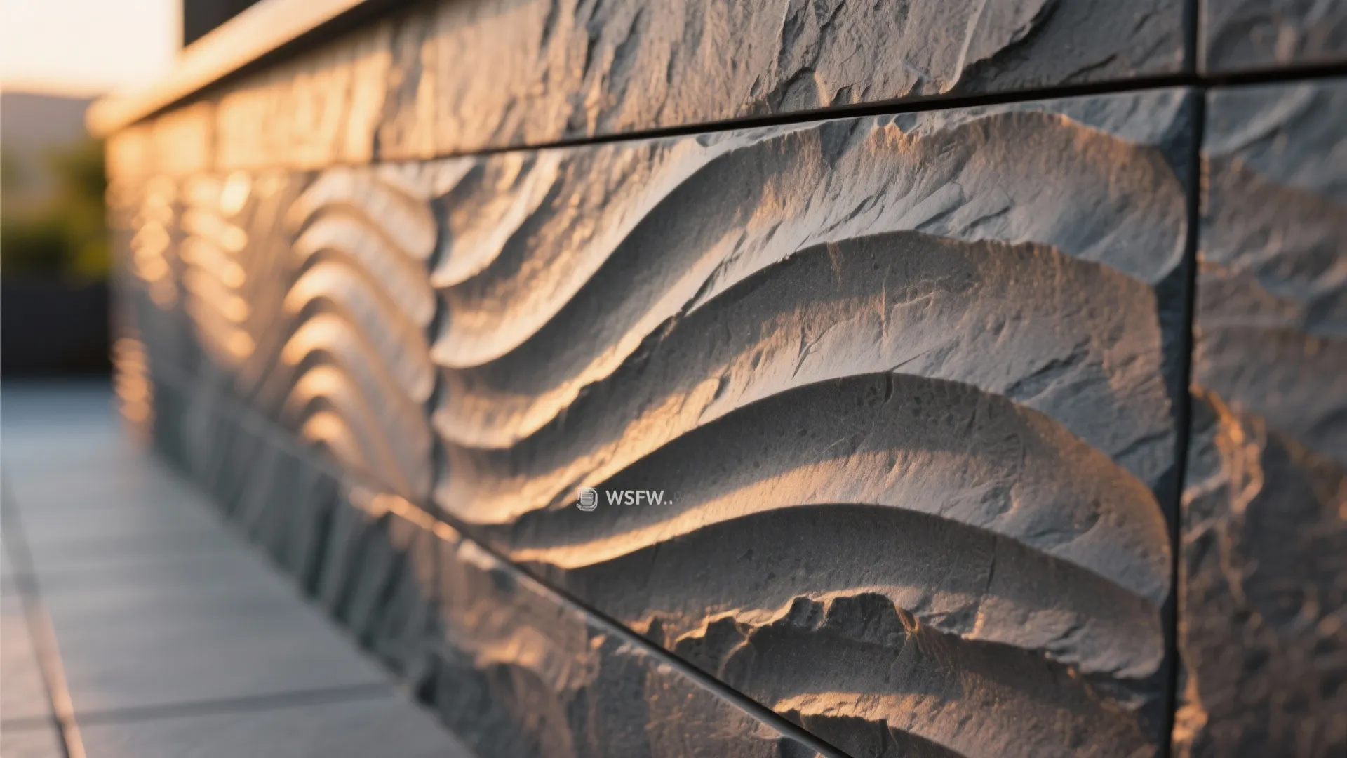 Close up of grey stone wall panel with wavy texture pattern in warm sunset light