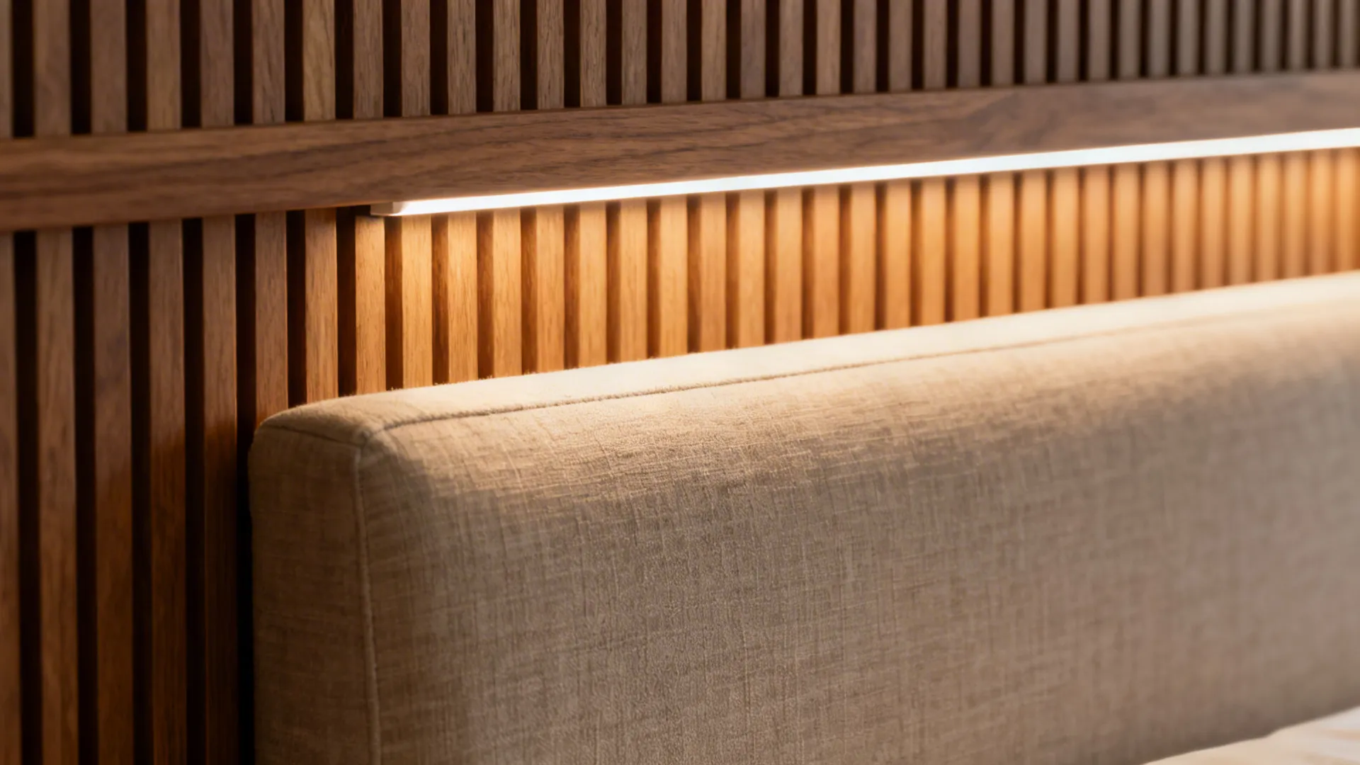 Beige fabric headboard against wood wall panel with integrated warm light fixture and soft lighting