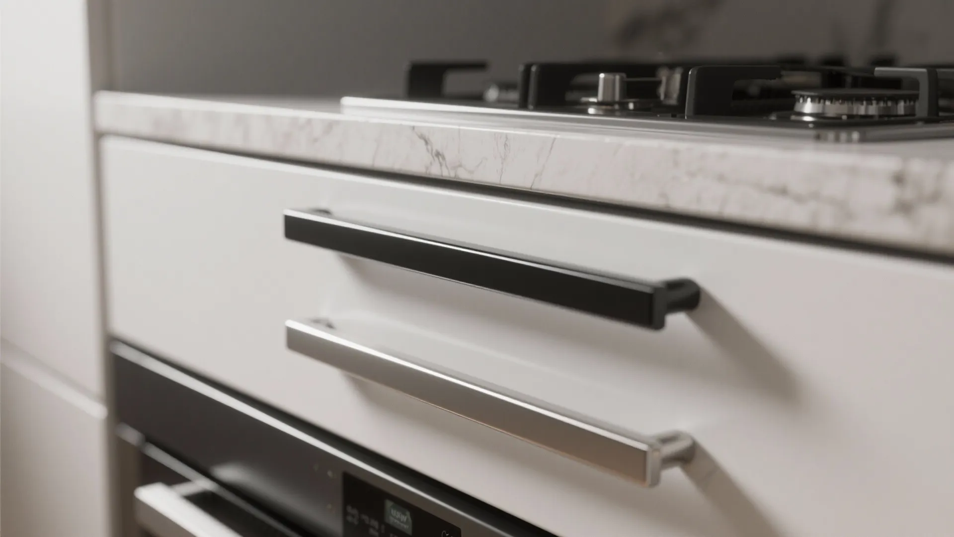 Close up of black and silver cabinet handles on white kitchen drawers with marble countertop