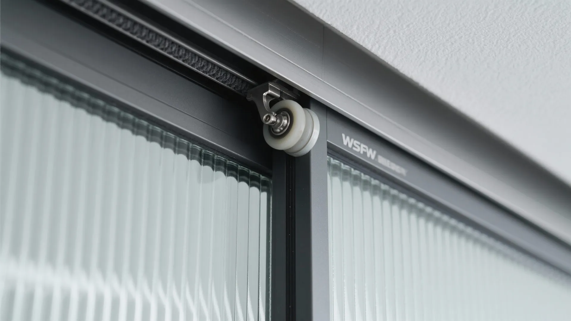 Close up view of metal sliding door track and roller system for glass room divider