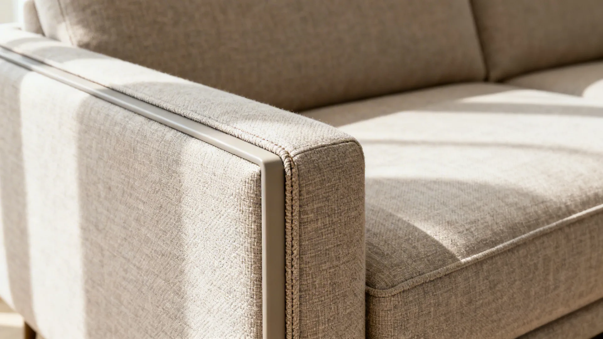 Close-up of mid-tone performance fabric and slim track arm with neat piping on a sofa.