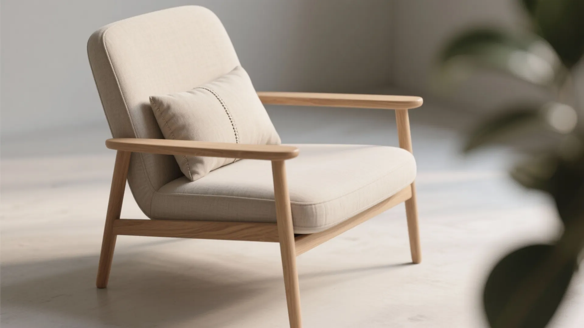 Minimalist beige armchair with wooden frame and small pillow sitting on a light floor surface
