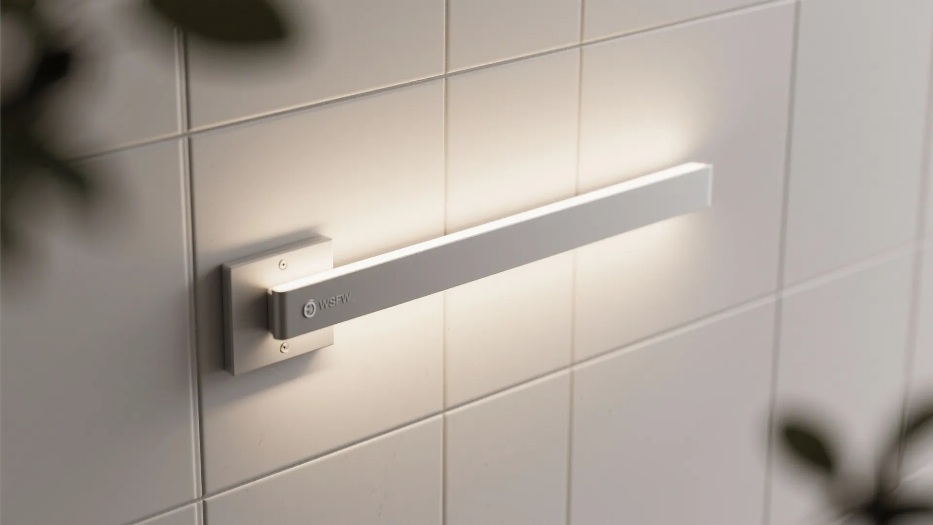 Modern silver wall light fixed on white bathroom tiles providing warm glow in minimal interior