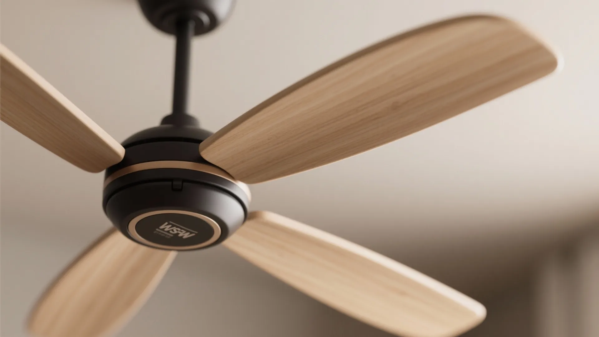 Close up of a modern ceiling fan with five light wood blades and black base