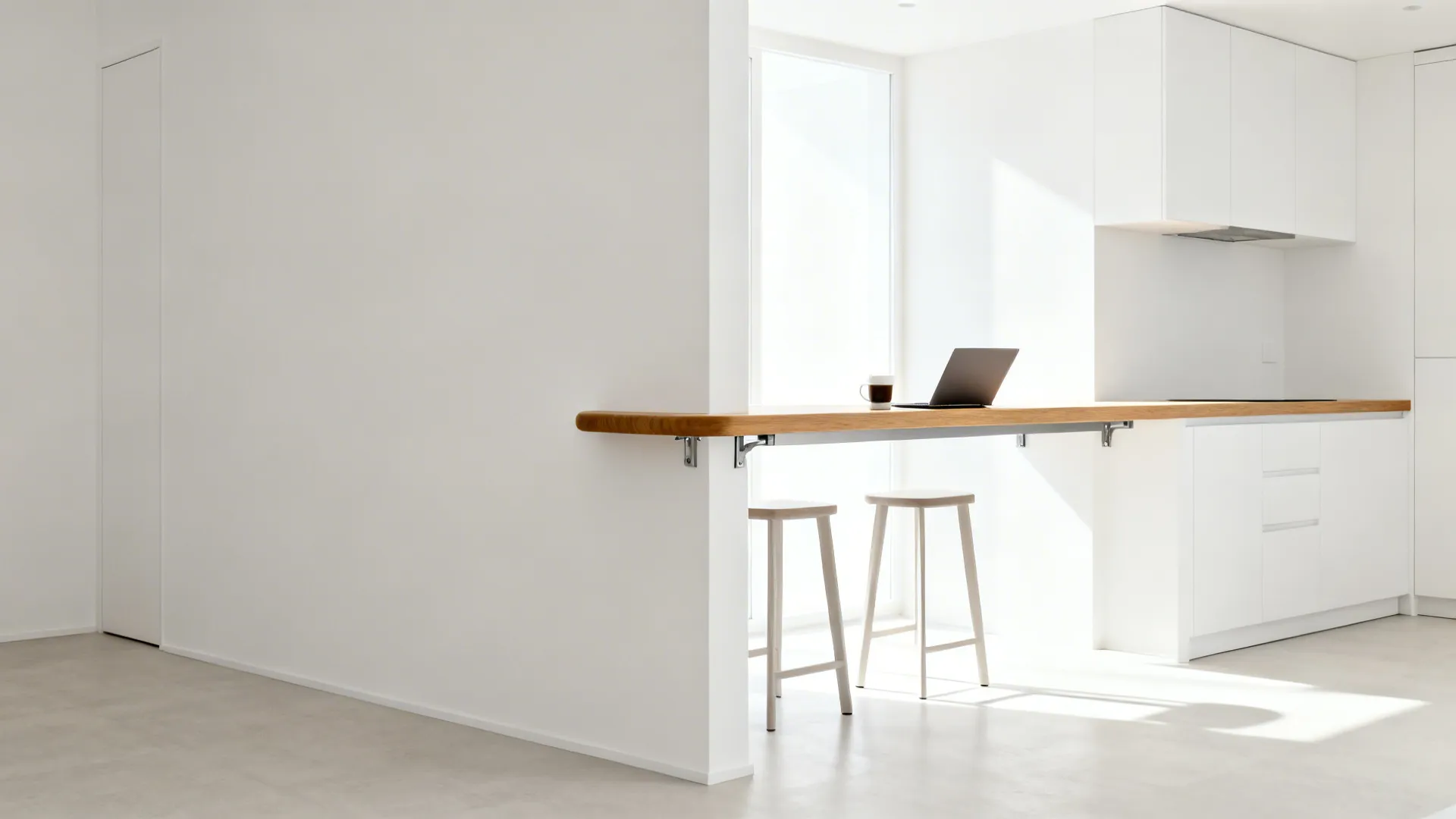 Modern white kitchen featuring a long wooden breakfast bar with two stools and a laptop