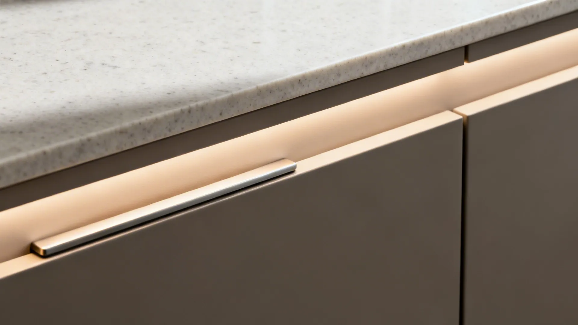 Macro of slim quartz edge, finger-pull rail, and recessed LED channel on matte cabinetry.