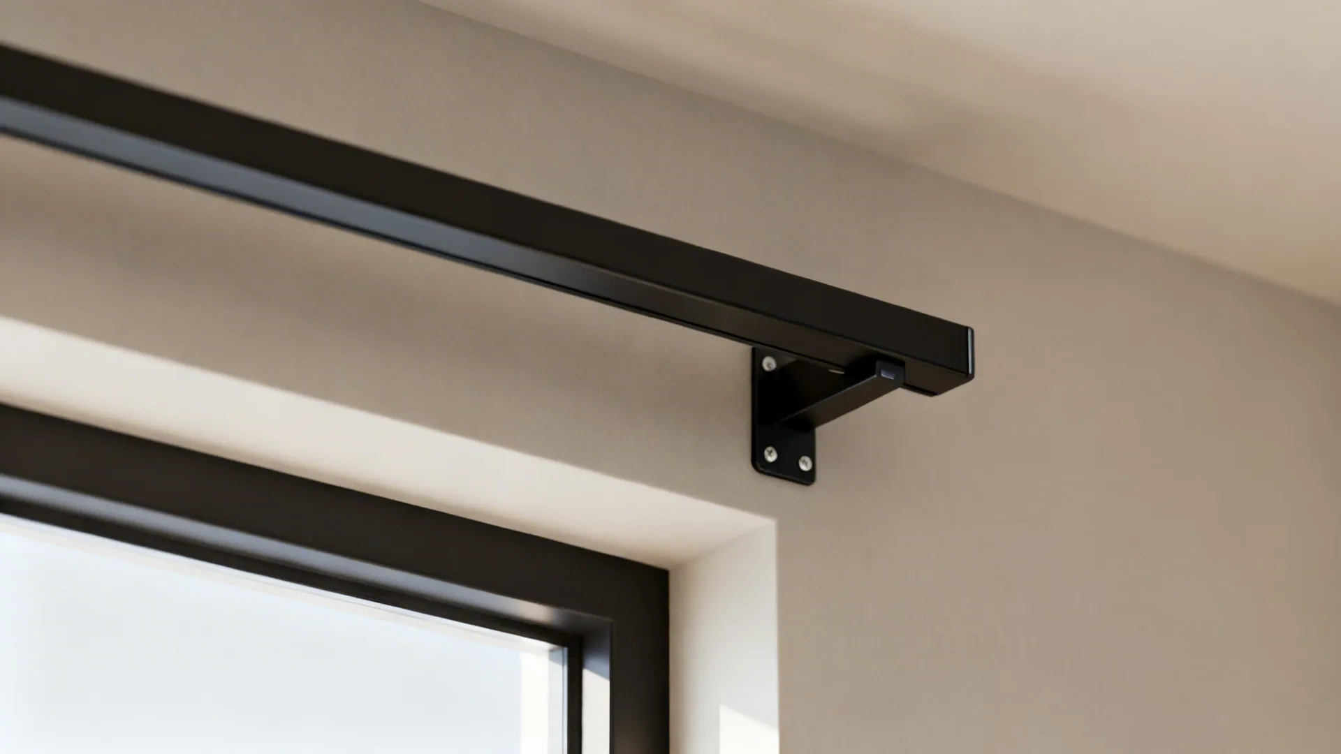 Black metal curtain rod attached to a wall above a window with a small metal bracket