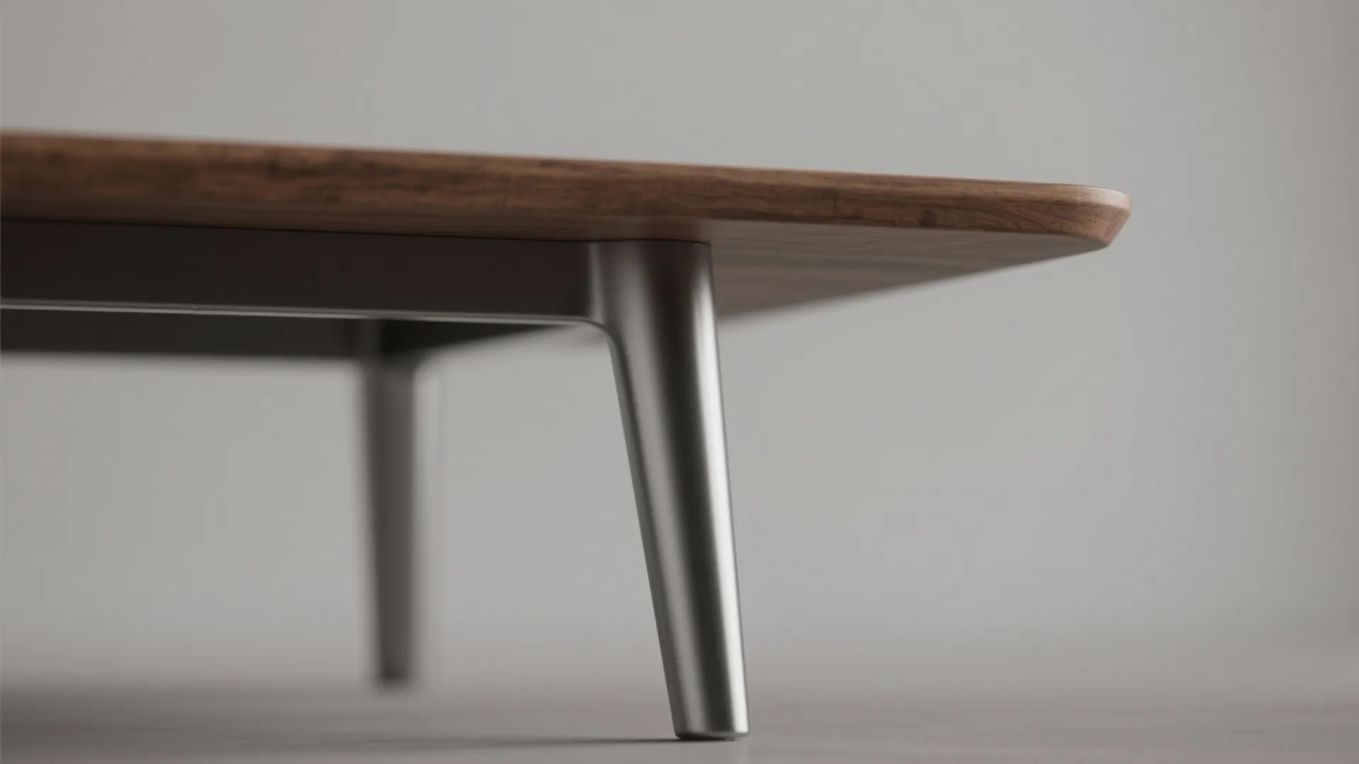 Macro detail of a tapered metal leg and thin oak tabletop edge showing lightweight materials.