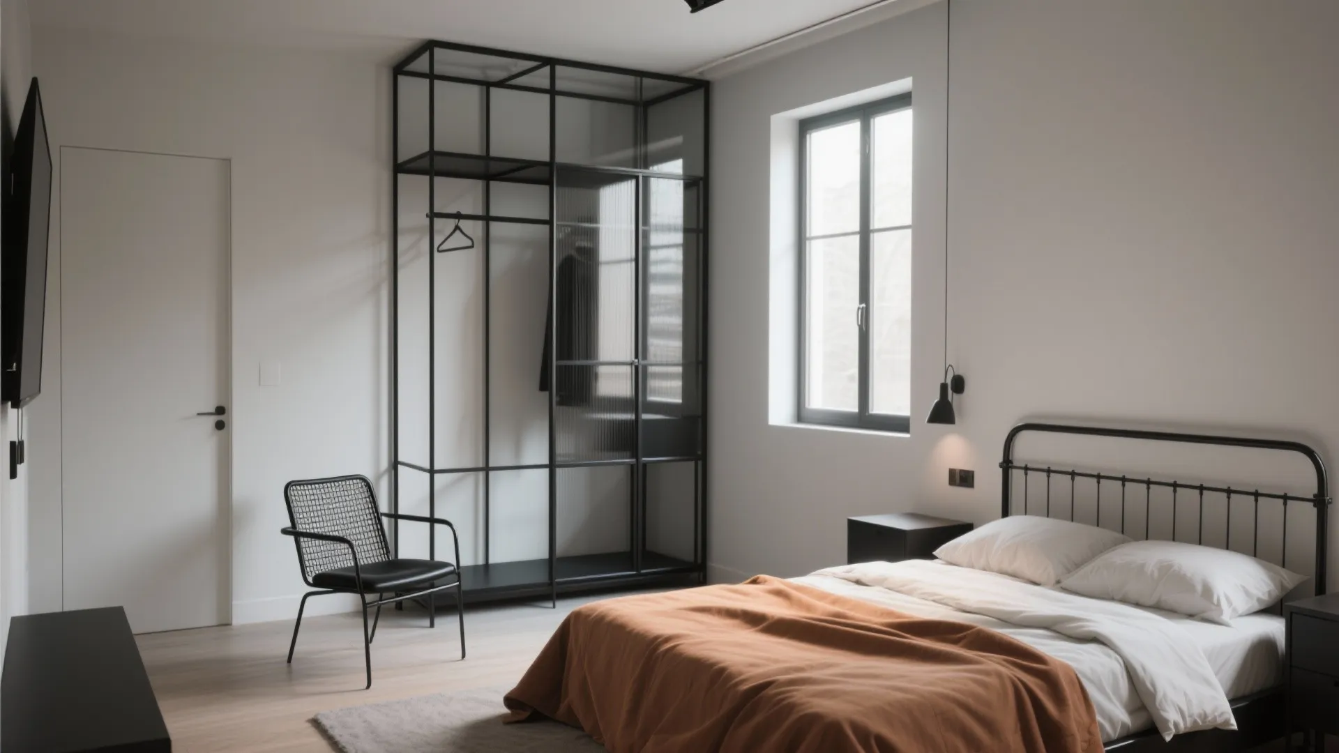 Minimalist bedroom with black metal bed frame plus orange blanket and a tall open rack
