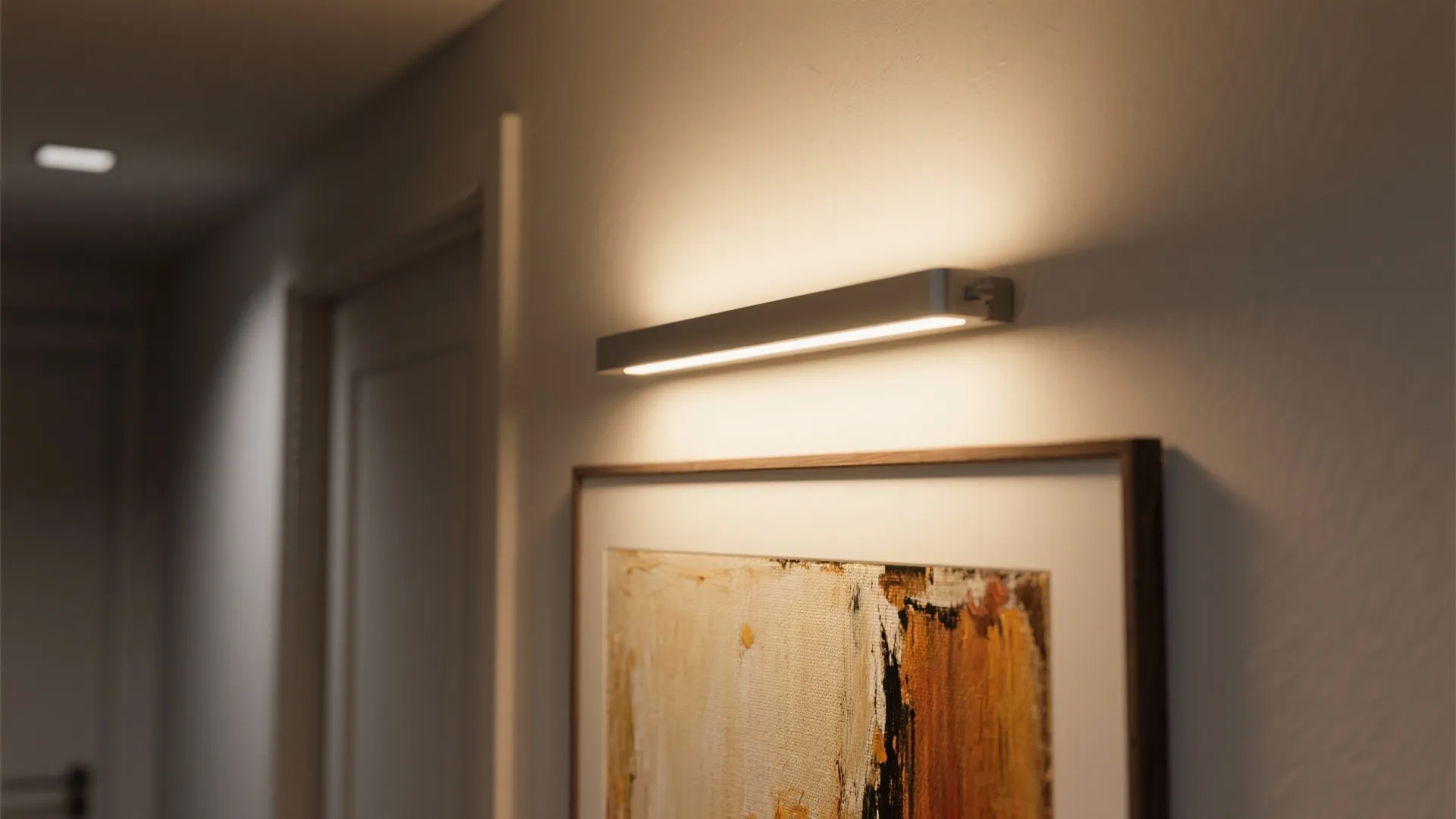 Slim low-profile picture light casting a warm focused beam on framed artwork, highlighting texture.