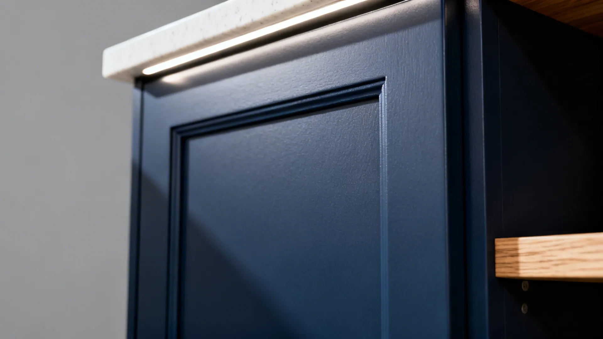 Macro detail of a matte navy slim-shaker door with an edge pull and subtle texture.