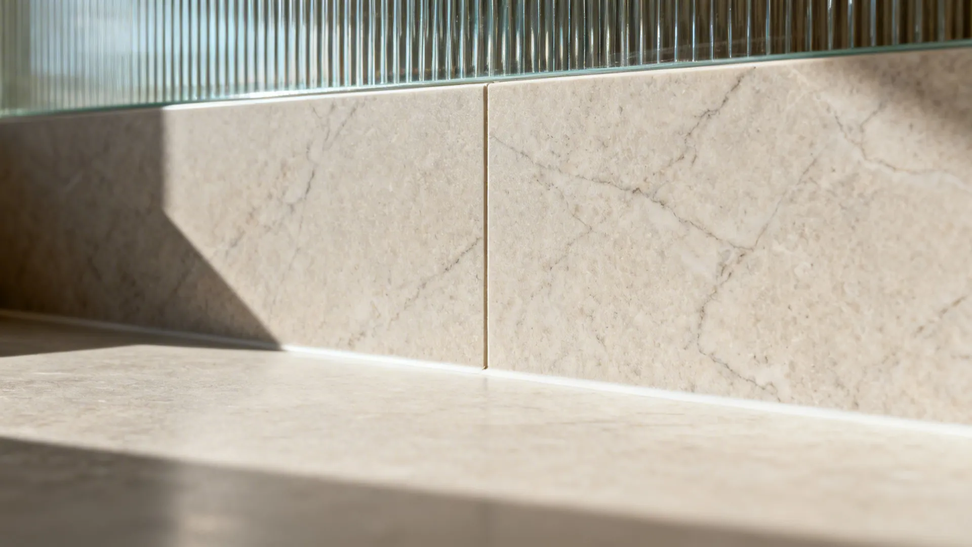 Close-up of a honed stone countertop with a slim matching backsplash showing a tight seam.