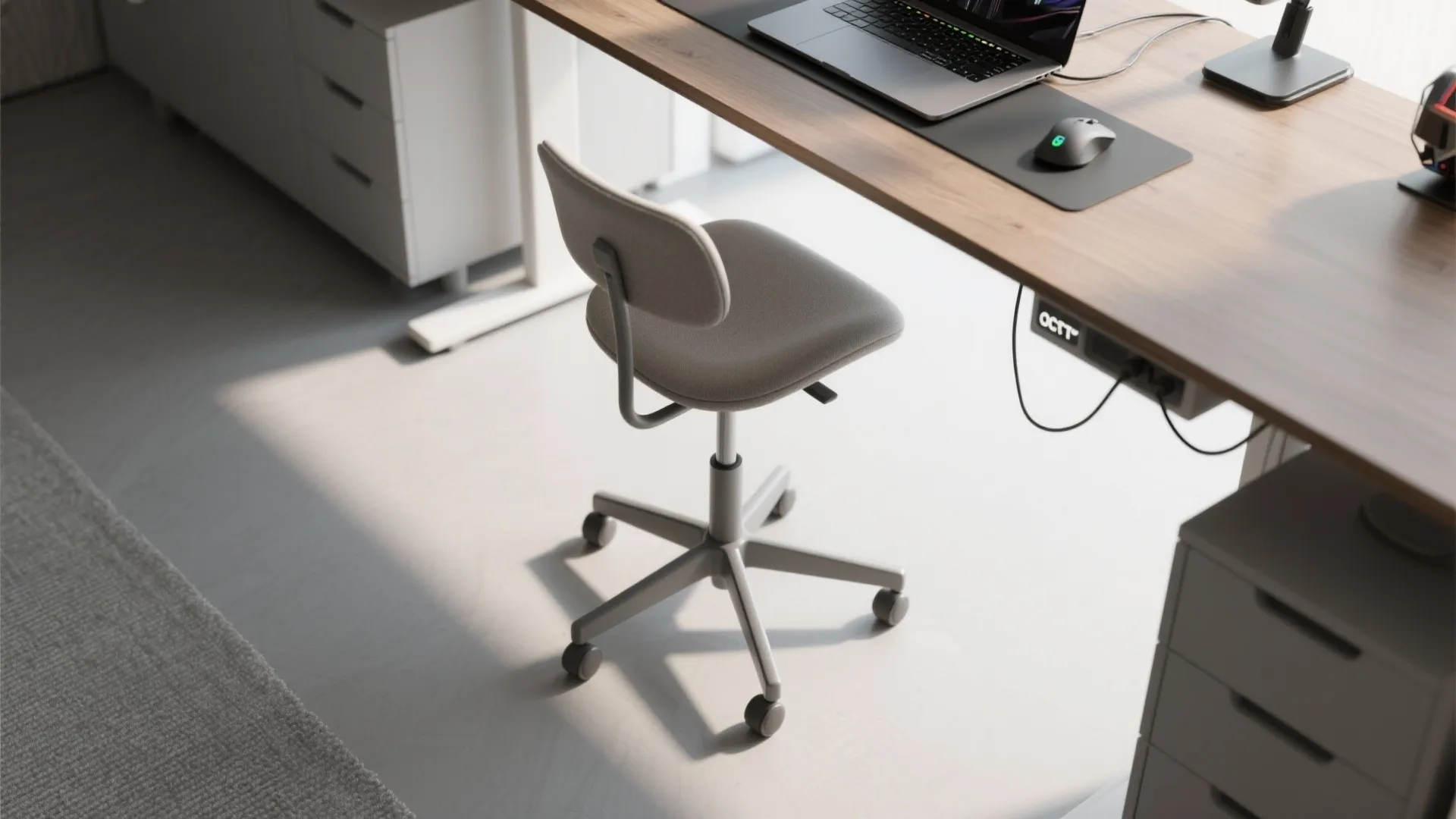 Top-down view of a slim swivel stool tucked under a multipurpose desk in a small home office and gaming setup.