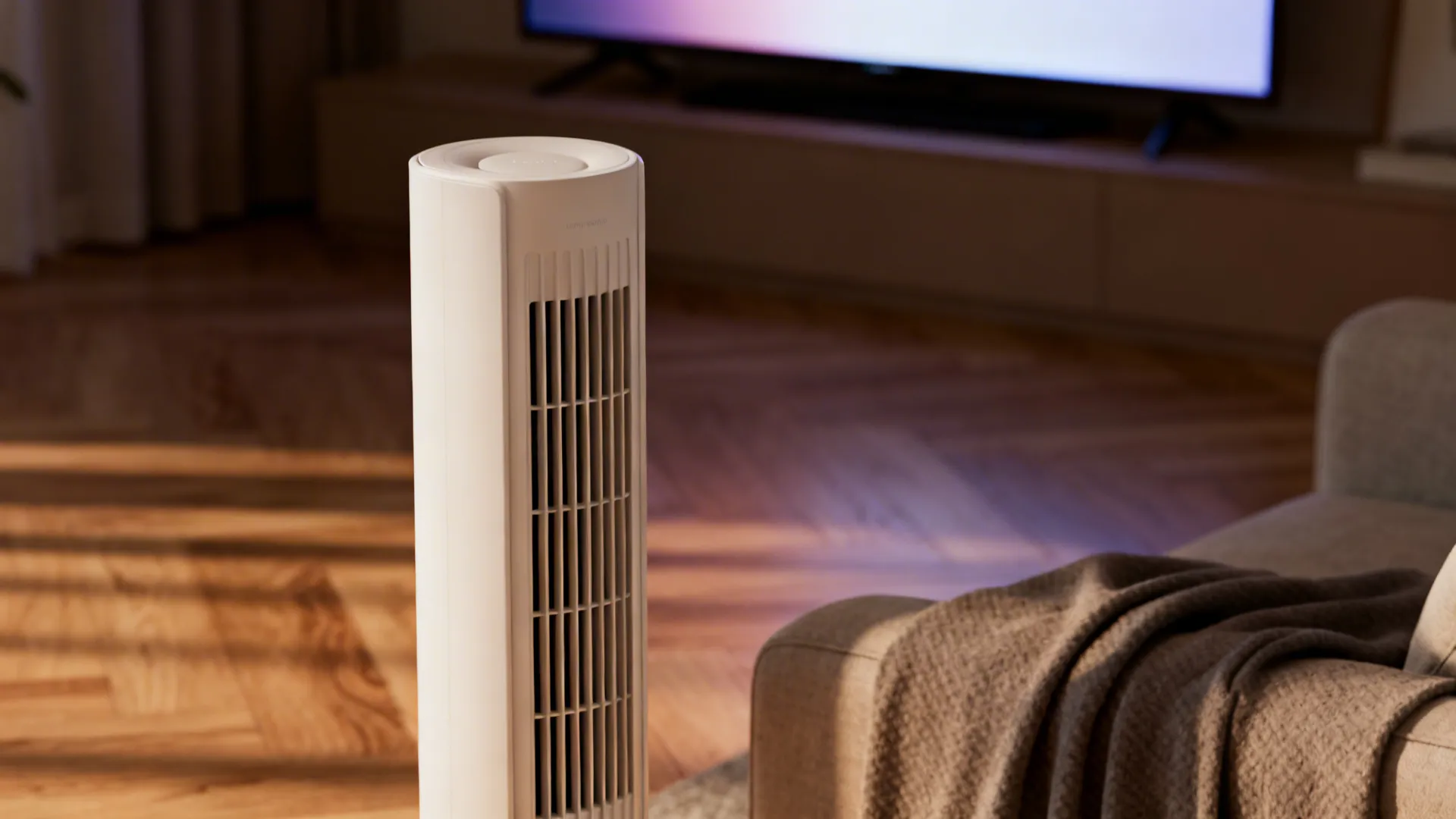 Close-up of a slim tower fan showing matte finish and grille near a TV setup
