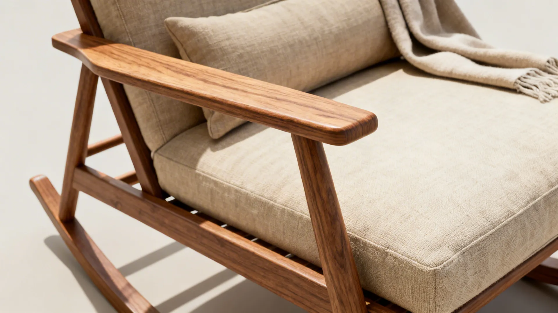 Close-up of a slim wooden rocking chair arm with a lumbar cushion and natural wood grain
